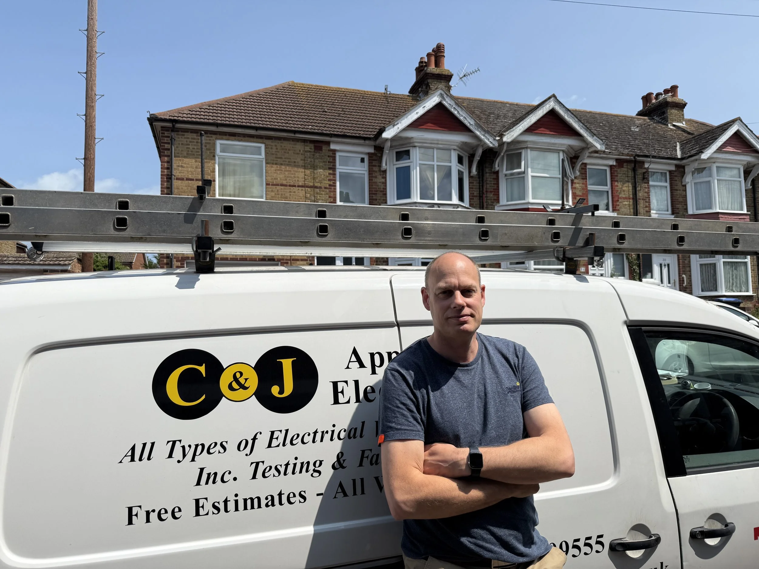 Electrician from C&J Approved Electricians Ltd standing next to branded company van.