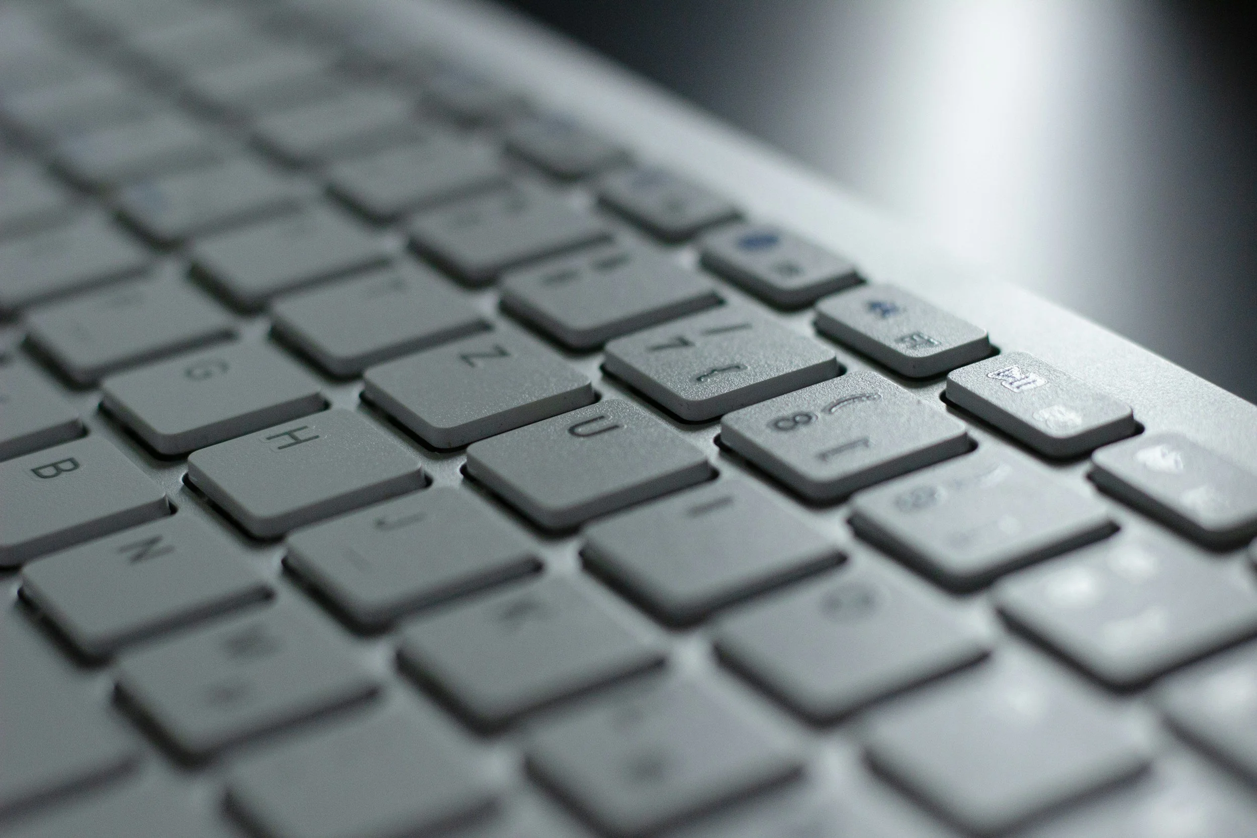 Close-up of a silver computer keyboard with black letters and symbols, showing the keys 'G', 'H', '2', and the arrow keys.