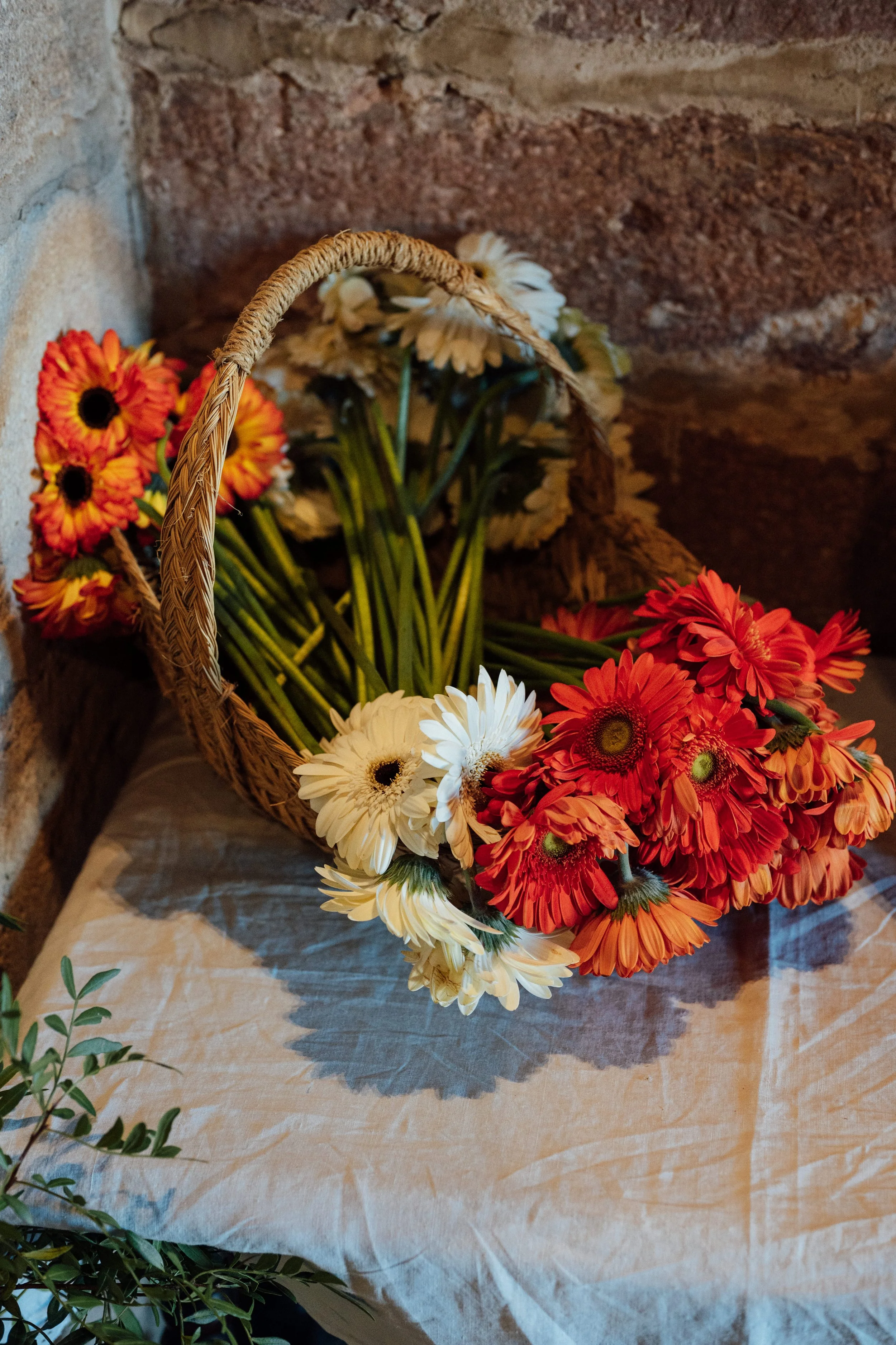 Un canasto con gerberas de color blanco, naranja y rojo, para la salida de la iglesia. 