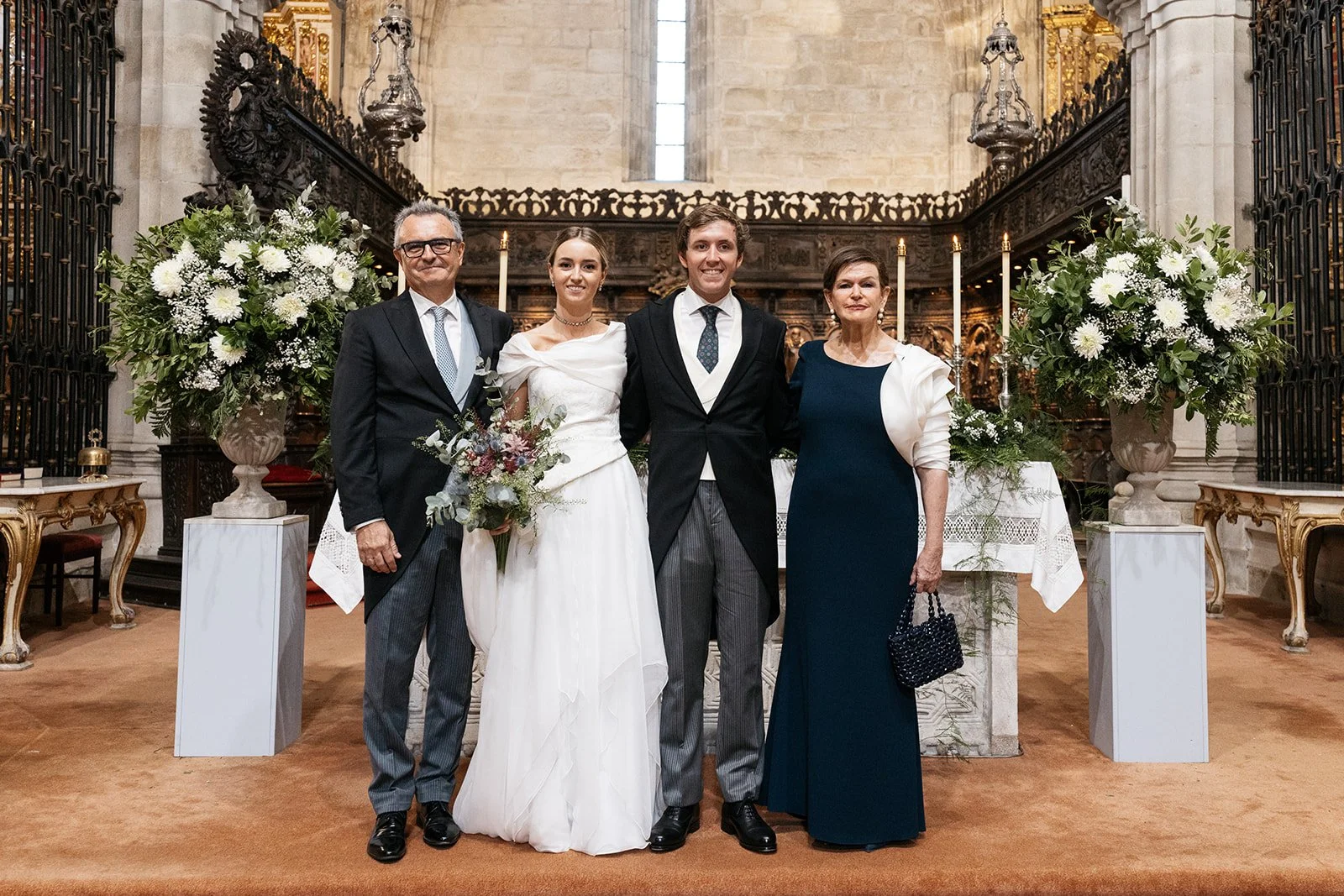 Novios y padrinos junto a la decoración floral de los pedestales dentro de la iglesia.