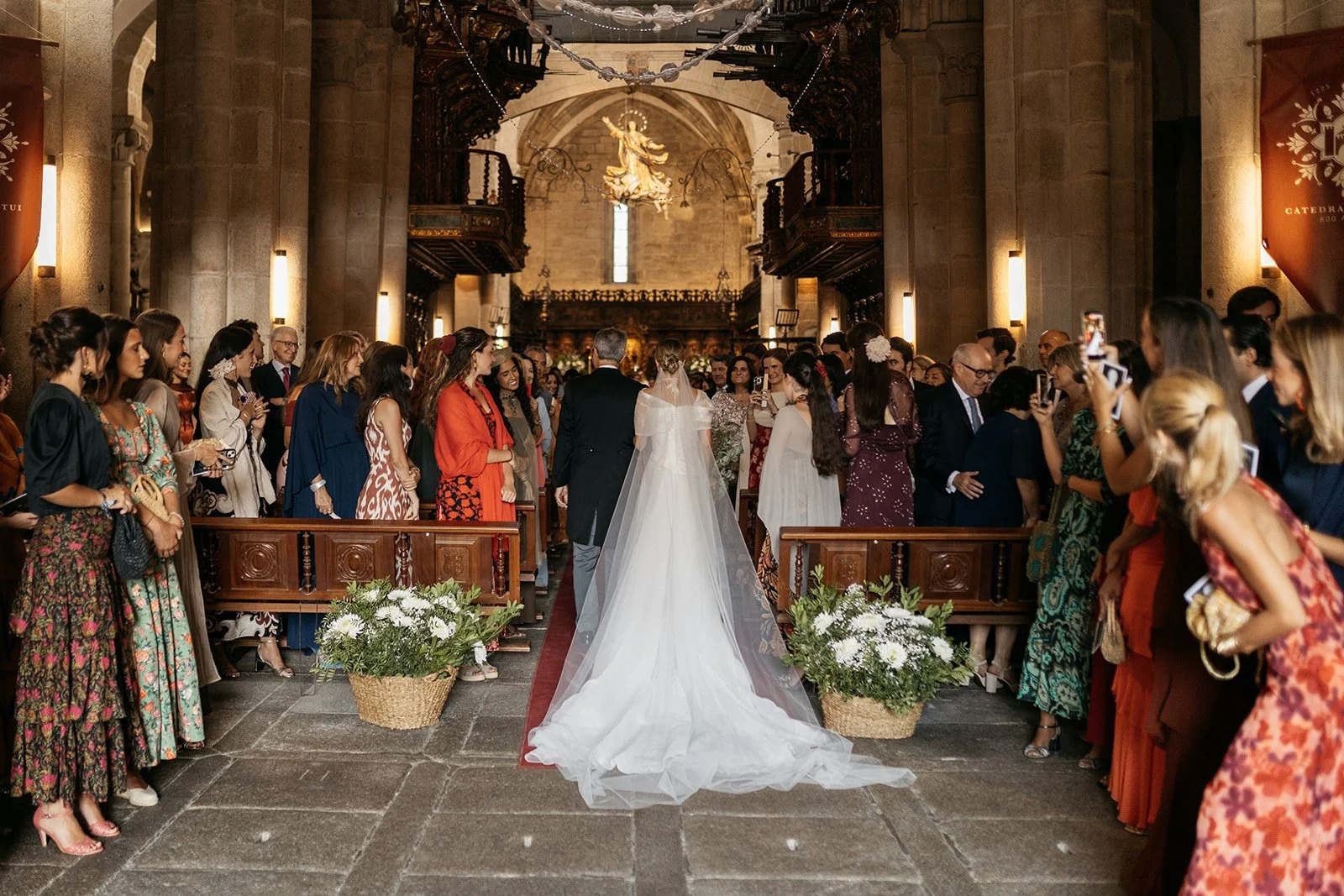 Entrada de la novia, con la decoración floral a los pies de la entrada en cestos de mimbre.