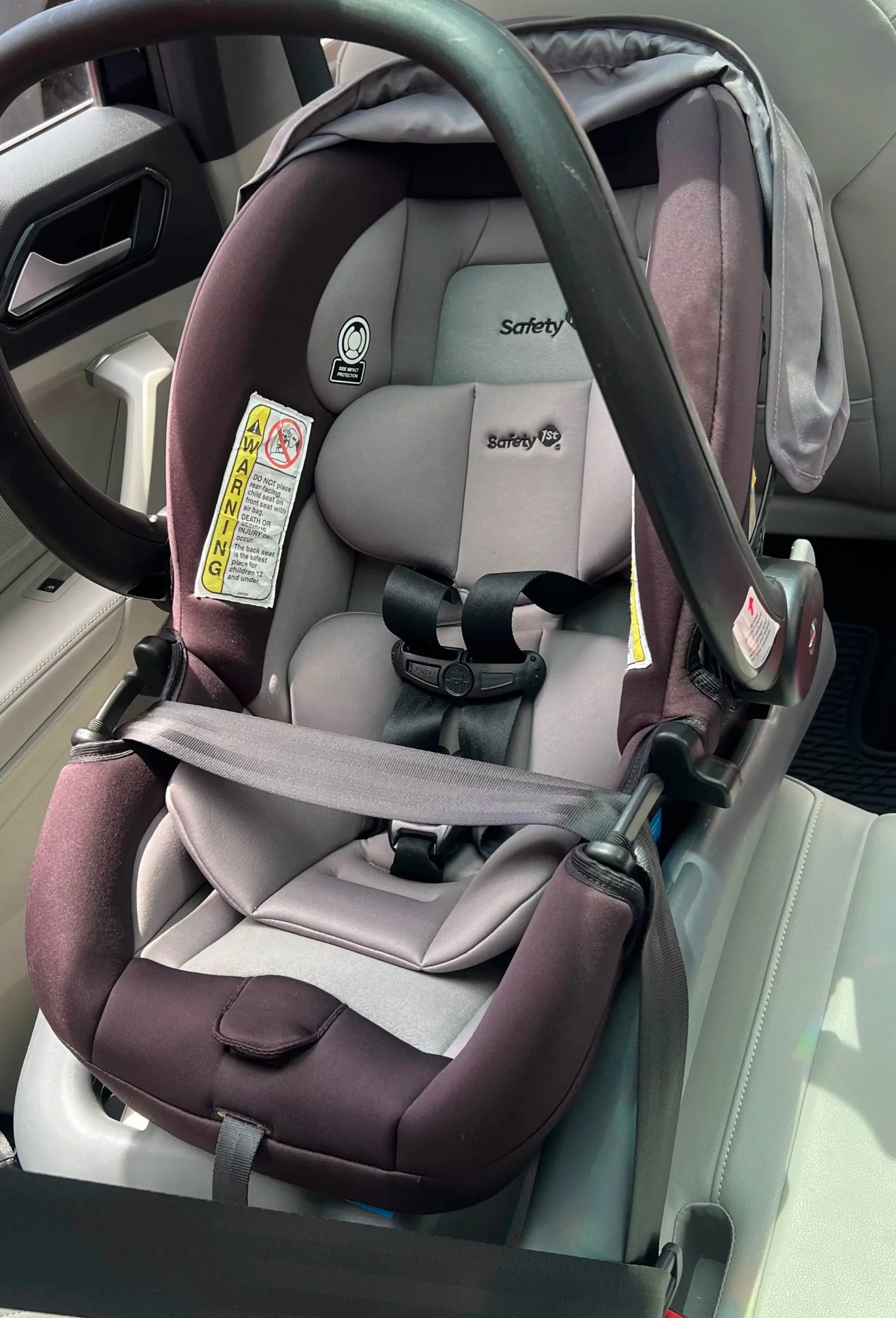Infant car seat installed in a vehicle, with padding, and harness.