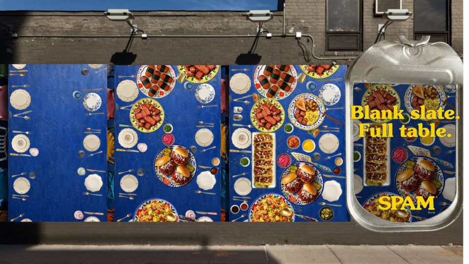 Several tables covered with colorful food dishes, mostly salads and appetizers, outdoors on a blue tablecloth, with a grocery store or service area on the side.