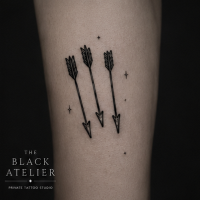Tattoo of three black arrows pointing downward, with small stars around them.