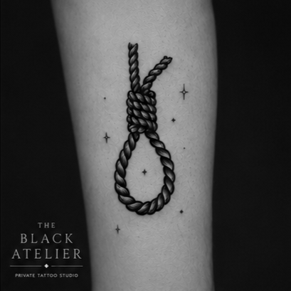 Tattoo of a hanging rope in the shape of a noose on a person's arm, with small stars around it, and the text "The Black Atelier Private Tattoo Studio" in the bottom left corner.