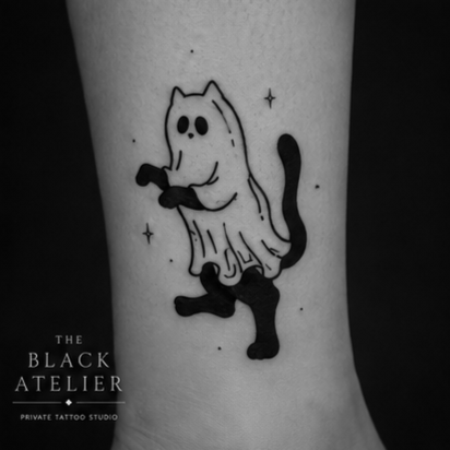Tattoo of a black cat with a ghostly sheet over its back, holding a small object, surrounded by small stars.