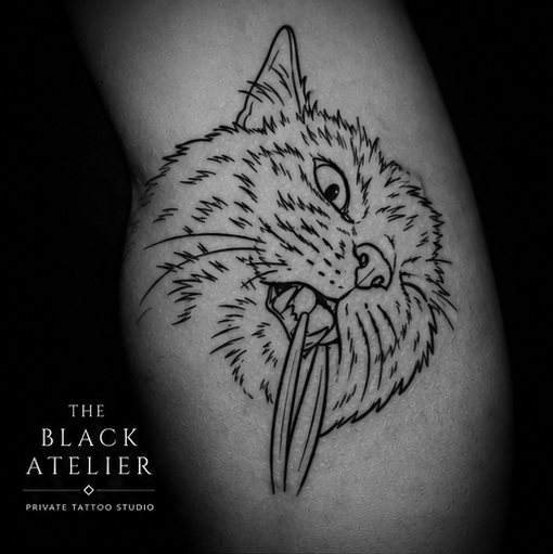 Black and gray tattoo of a wildcat with its tongue sticking out, on a person's skin.