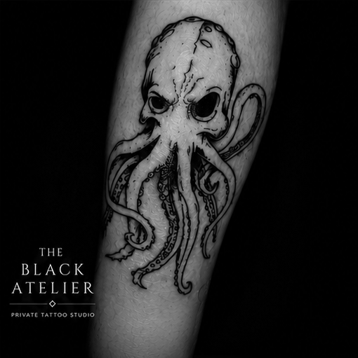 Tattoo of a stylized octopus with a skull-like head on a person's arm.