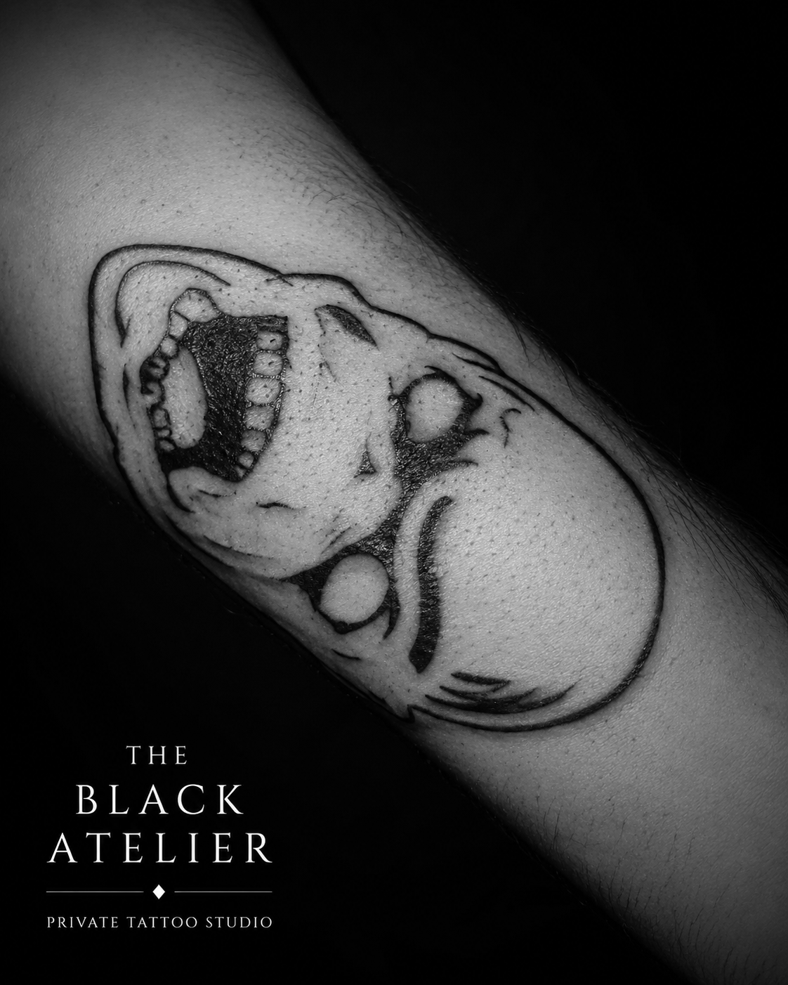 Black and white tattoo of a dinosaur skull on a person's arm, with text overlay reading 'The Black Atelier Private Tattoo Studio'.
