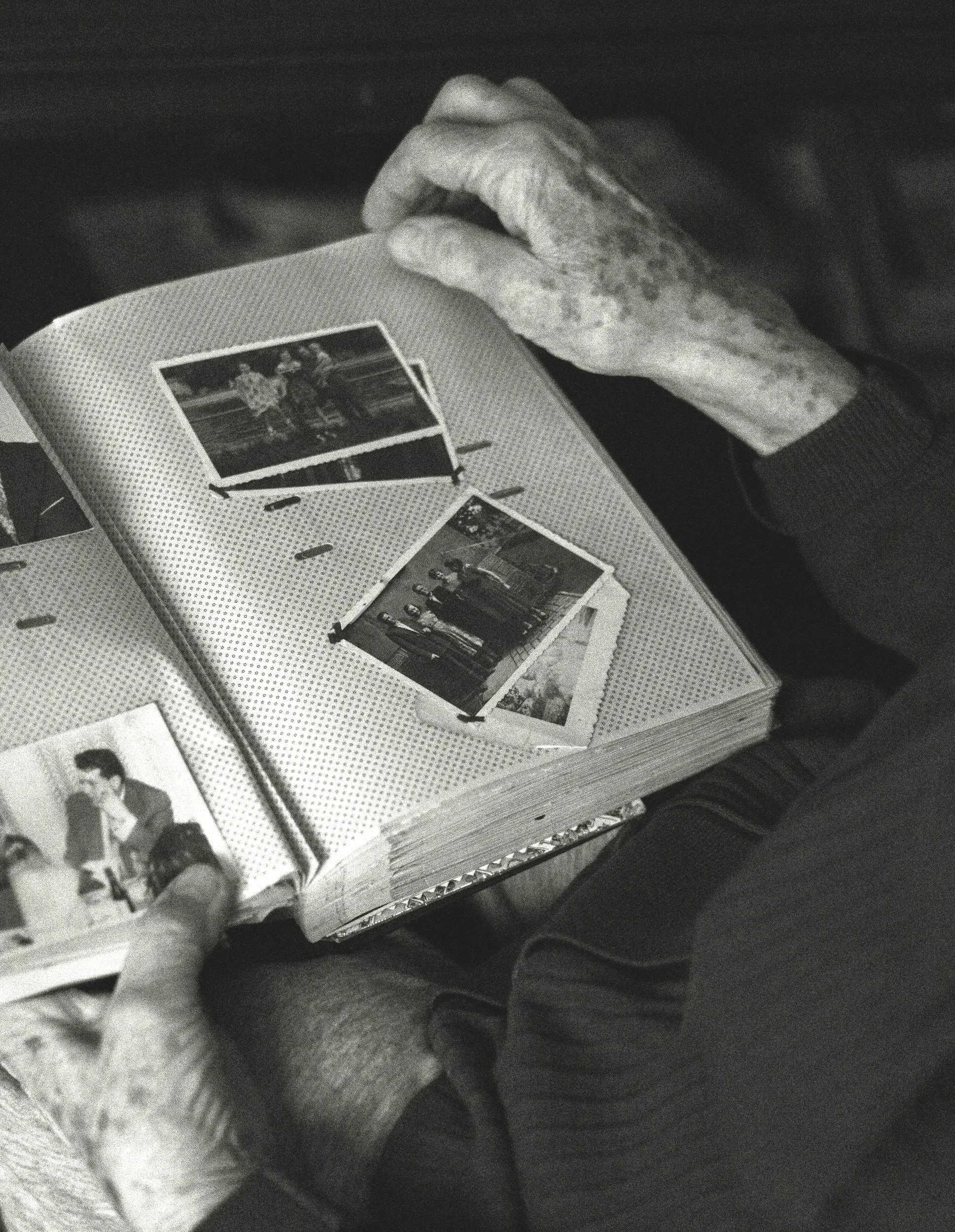 Elderly hands holding a cherished family photo album — compassionate downsizing and life transition organizing services in mid-coast Maine