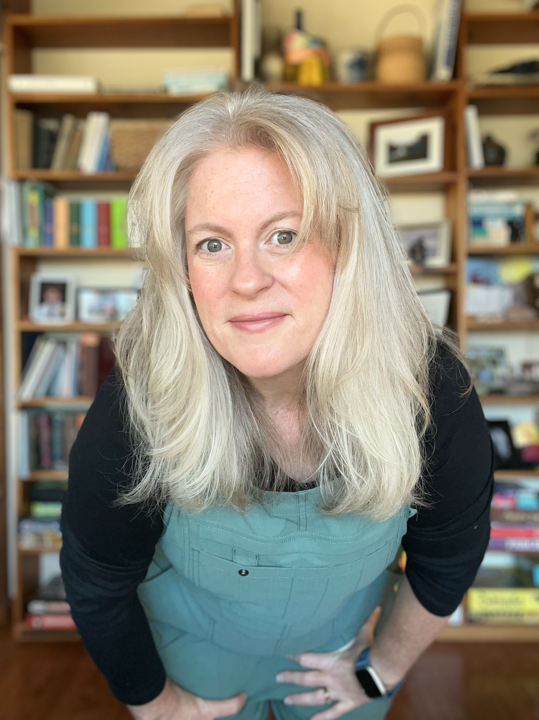Rebecca Waddle, professional home organizer serving Harpswell and mid-coast Maine, standing in front of an organized home bookshelf.