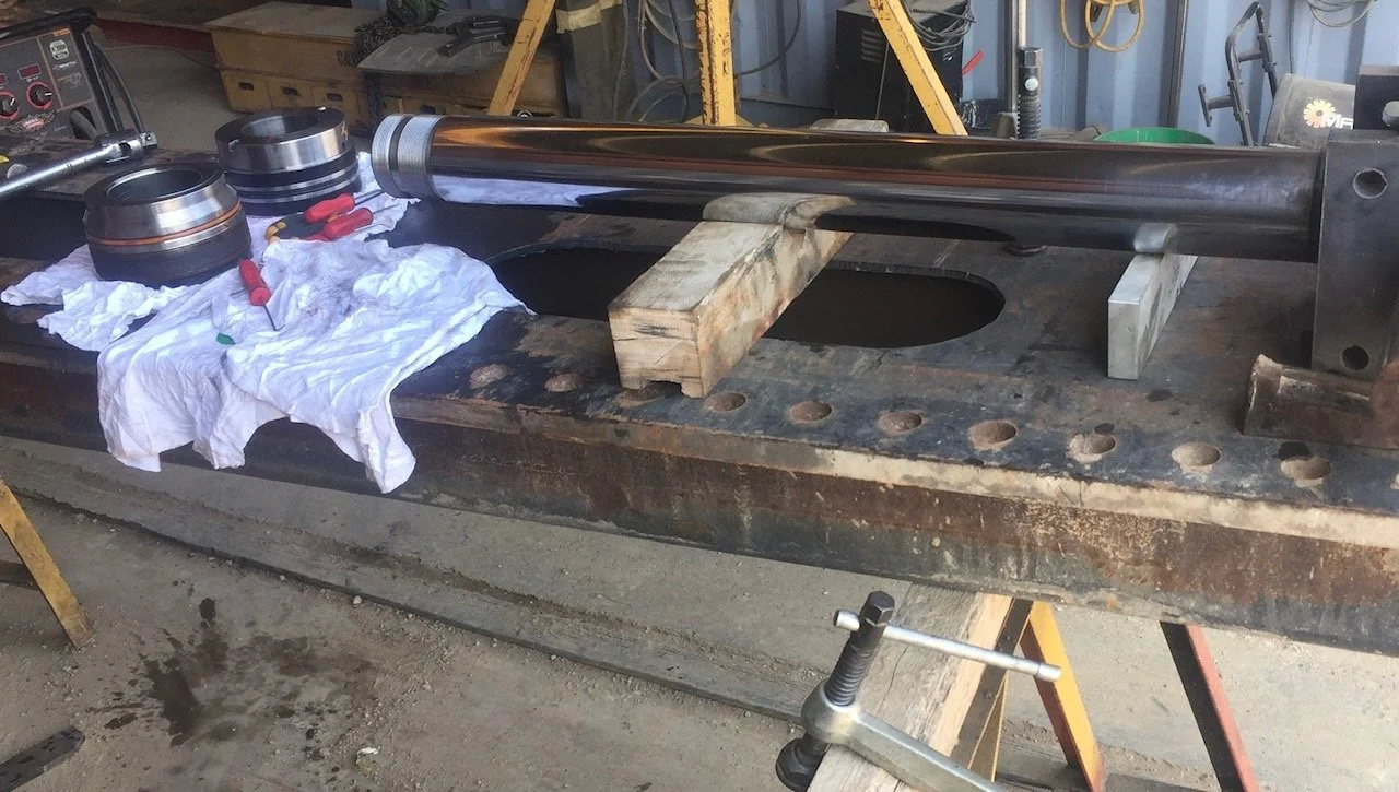 Heavy equipment repair, excavator hydraulic cylinder rebuild in progress.