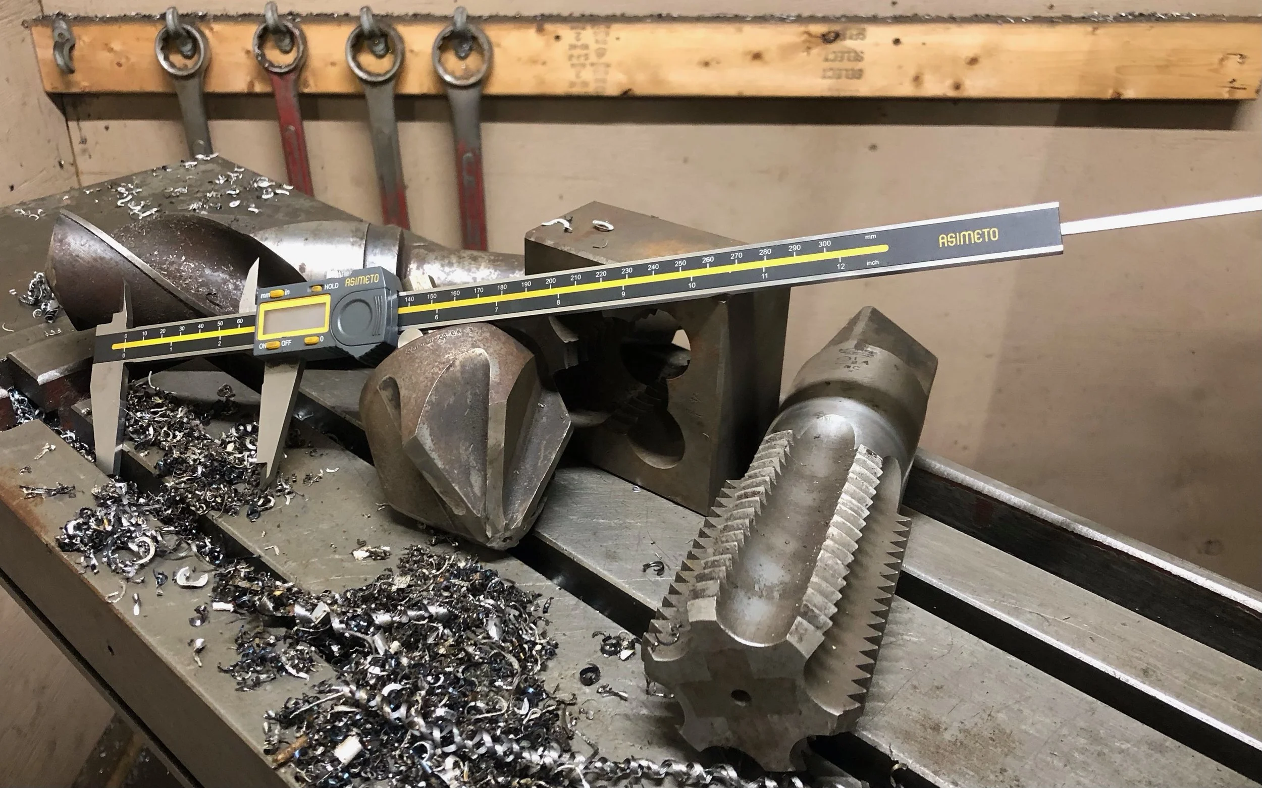 Machining tools, large 2 1/2-inch tap, die, and countersink on a machining table.
