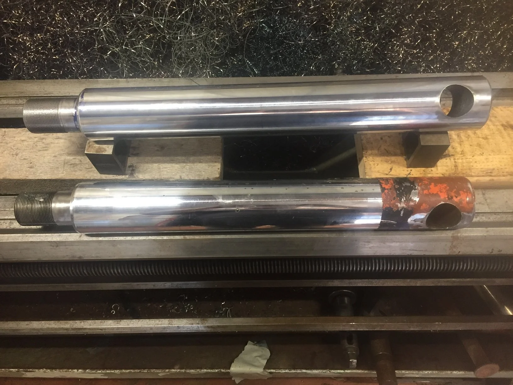 Heavy equipment repair, old and new hydraulic cylinder rod comparison for replacement.