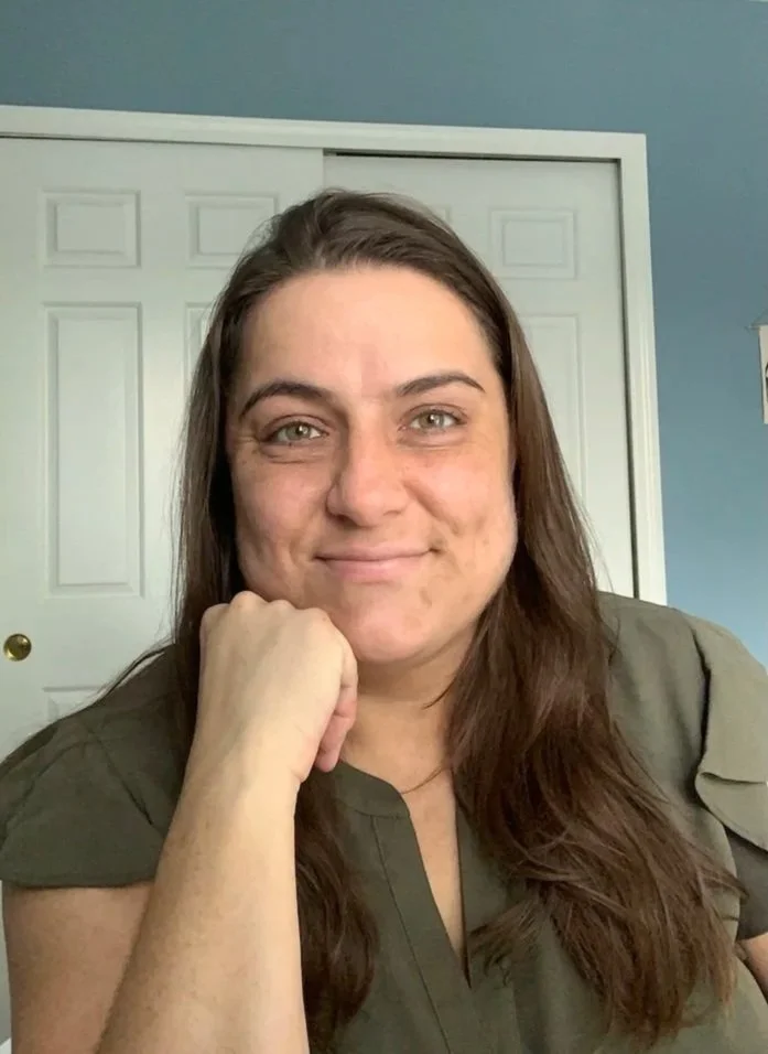Dr. Katie, a psychotherapist with long brown hair, smiling in her therapy office.