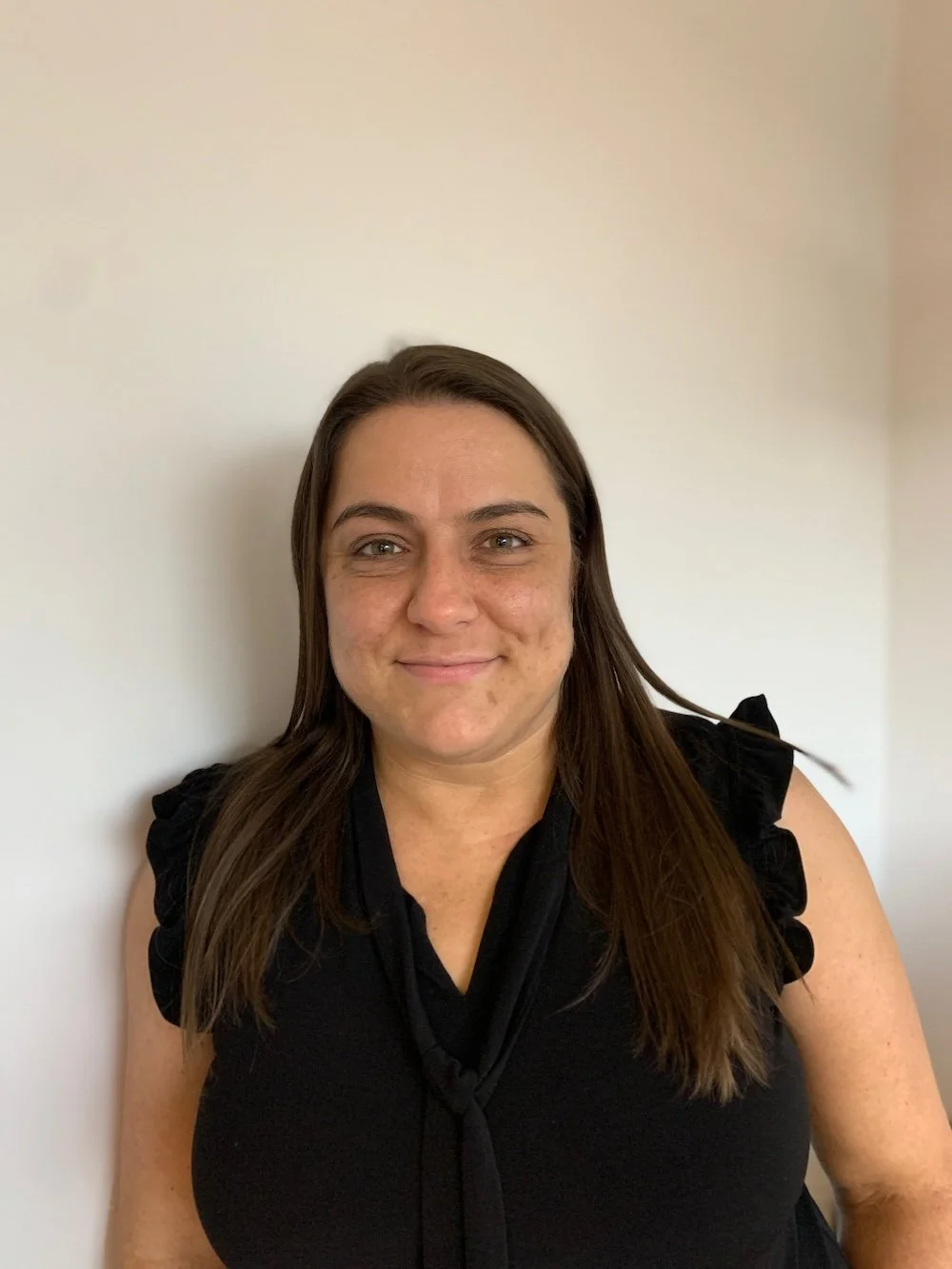 Dr. Katie, a psychotherapist with long brown hair, smiling in her therapy office.