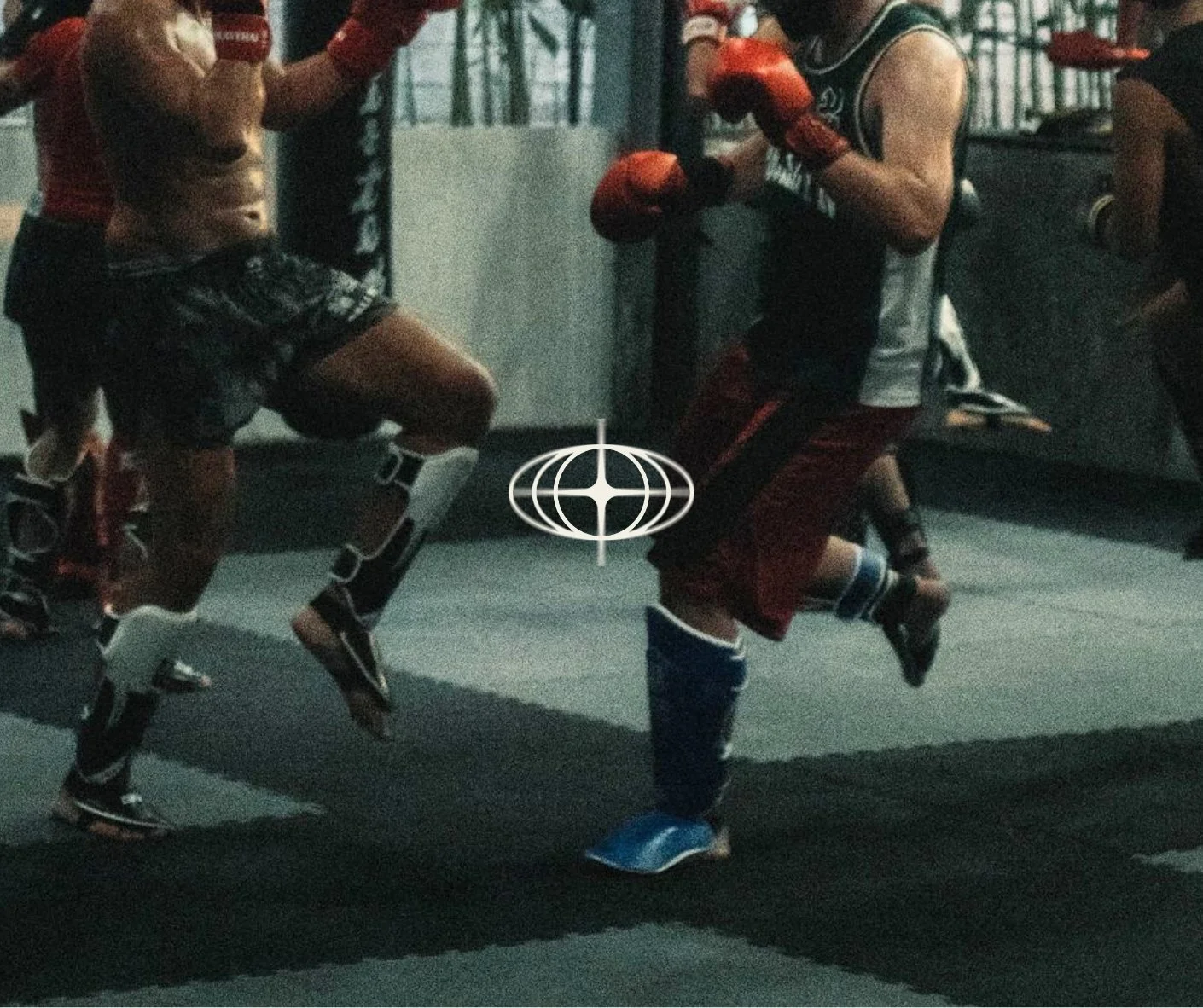 Deux jeunes hommes s'entraînent en faisant du kick boxing dans une salle, portant des gants de boxe et des équipements de protection.