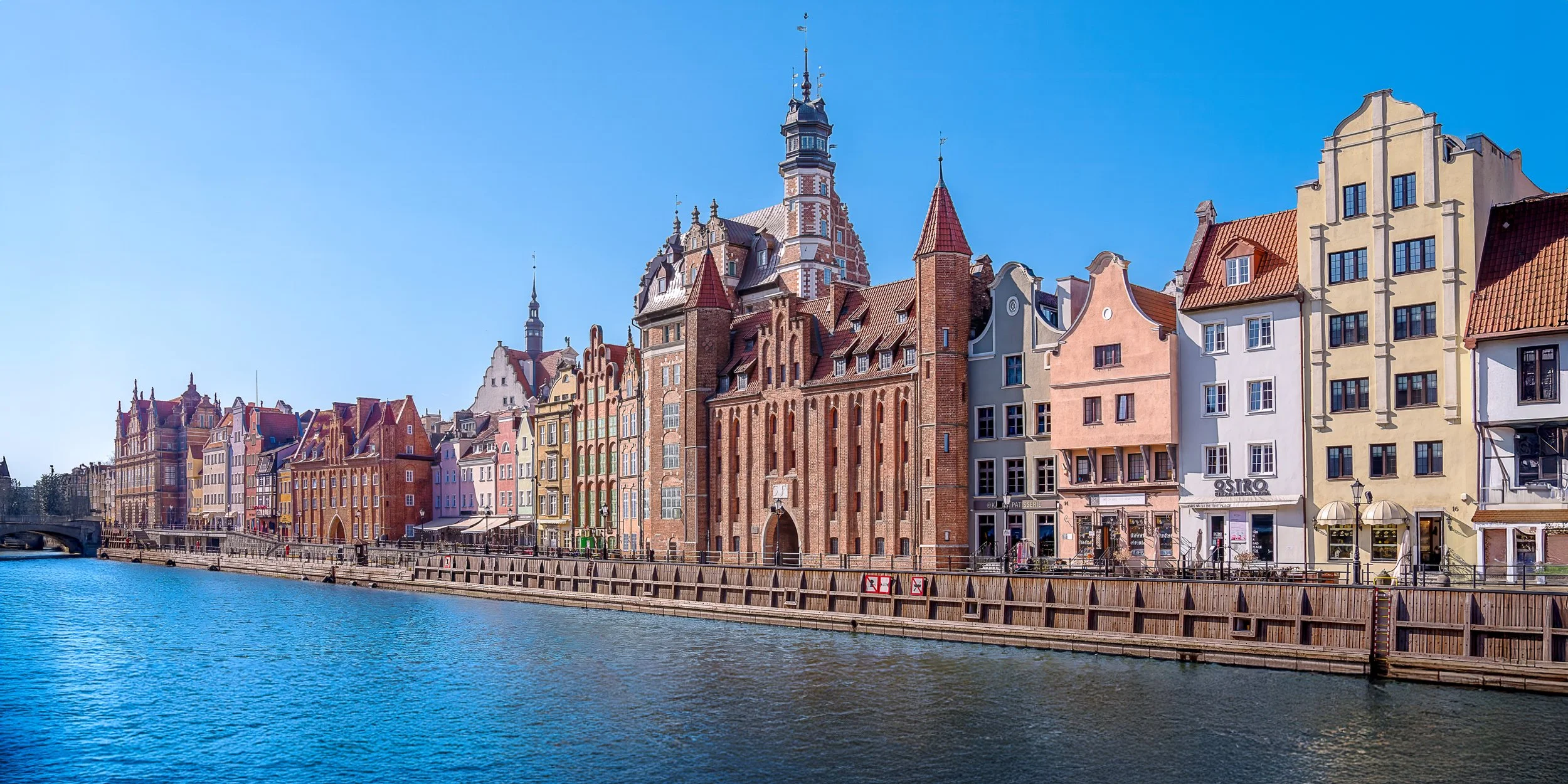 Colorful historic buildings lining a canal under a clear blue sky.