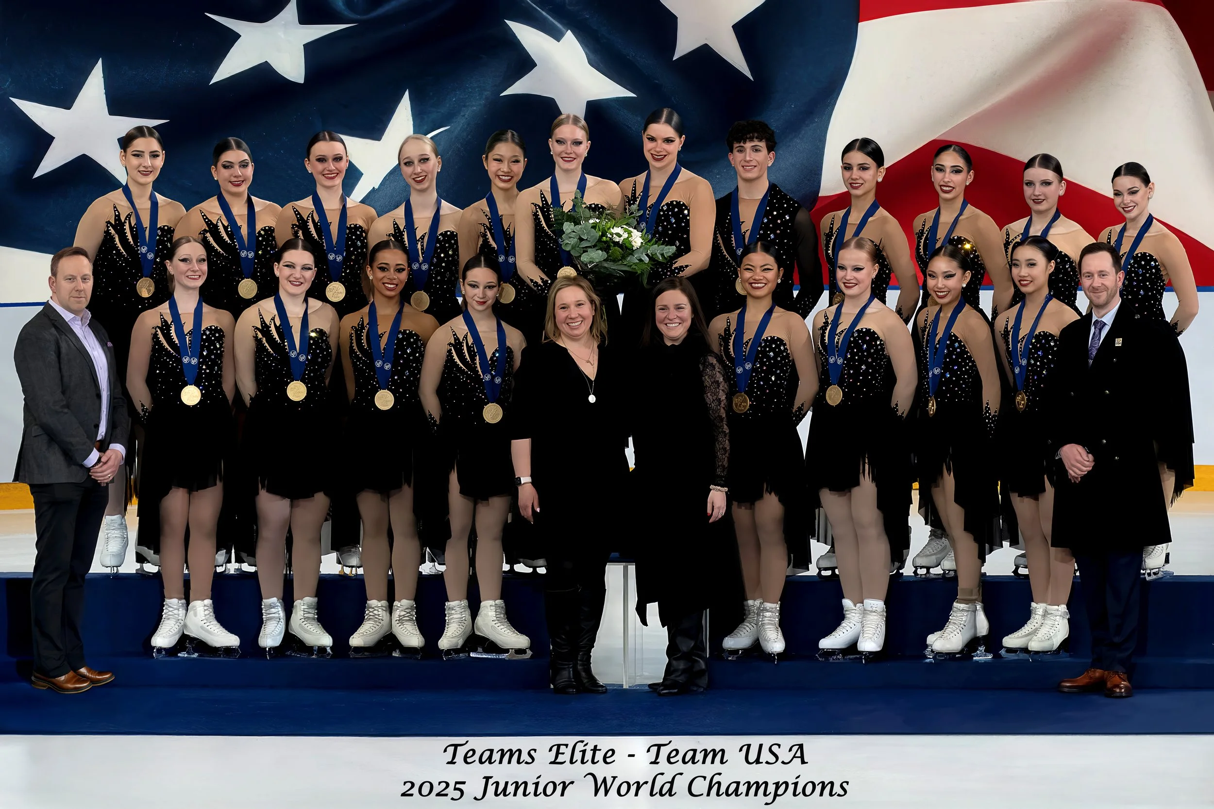 A group of young female ice skaters wearing black costumes with sparkles and medals around their necks, posing with coaches and officials in front of a large American flag background, celebrating their victory as 2025 Junior World Champions.