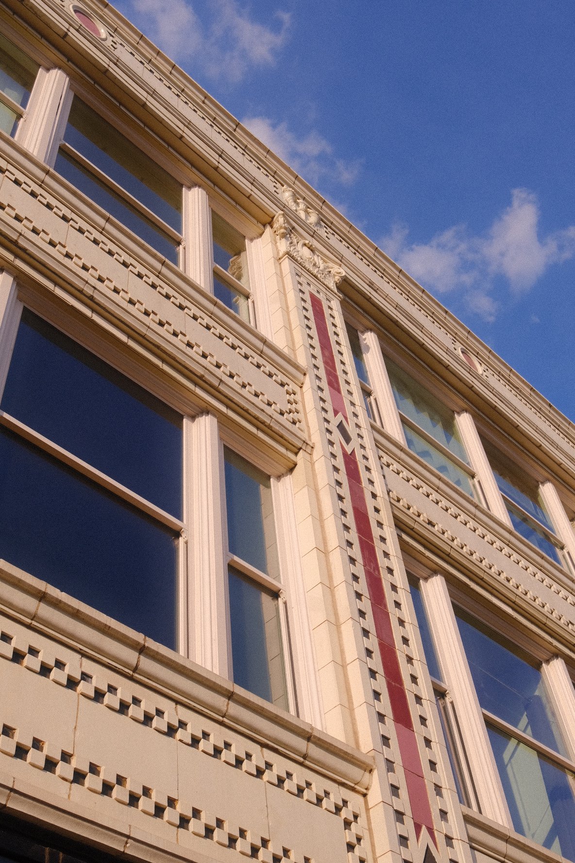 Close-up view of a historic multi-story building's facade with ornate architectural details and large windows set against a partly cloudy sky. Fine Arts Lofts in Wicker Park Chicago.