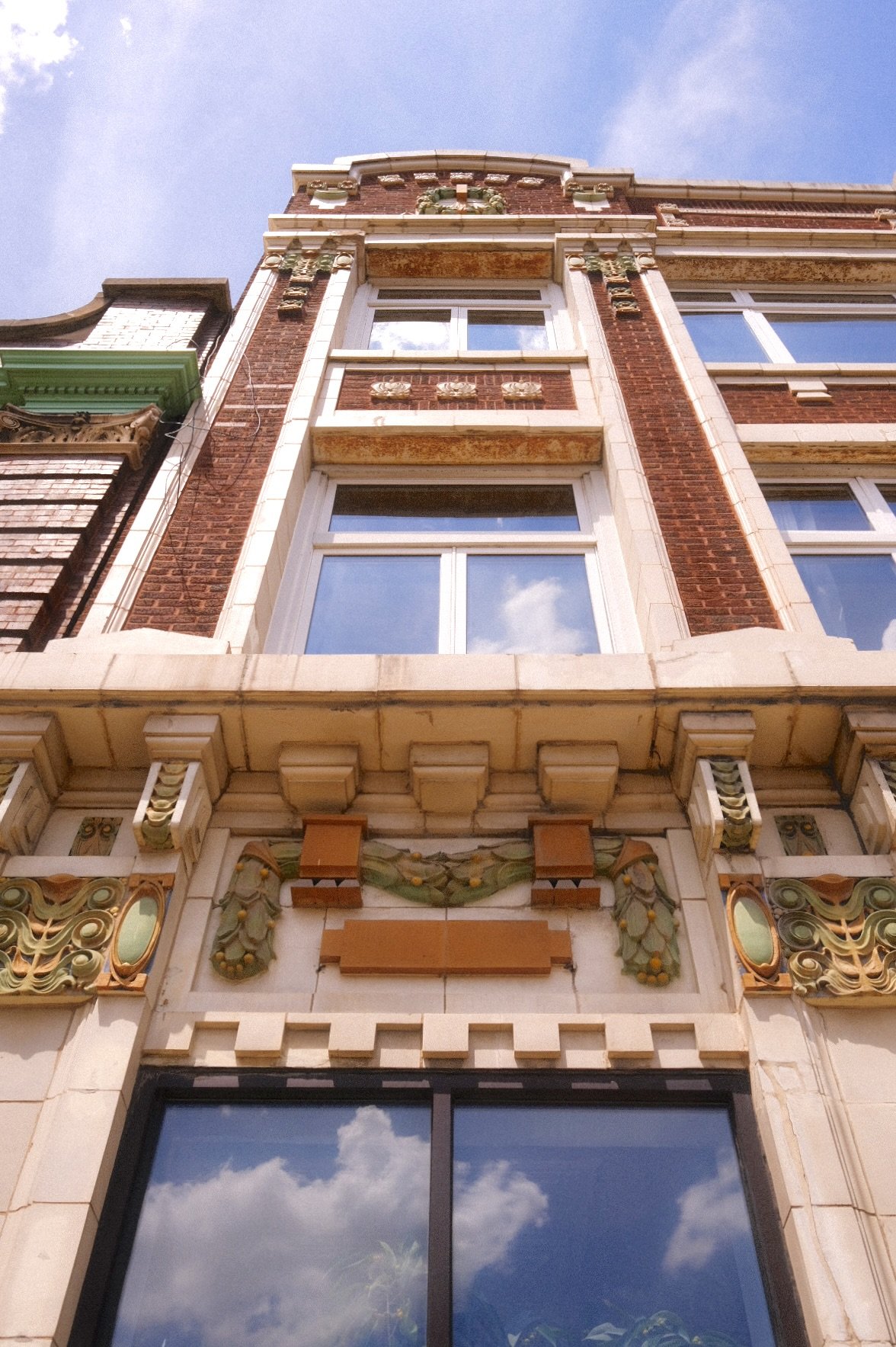 Close-up view of an ornate, historic building facade in Humboldt Park with decorative architectural elements, brickwork, and large windows reflecting the sky.