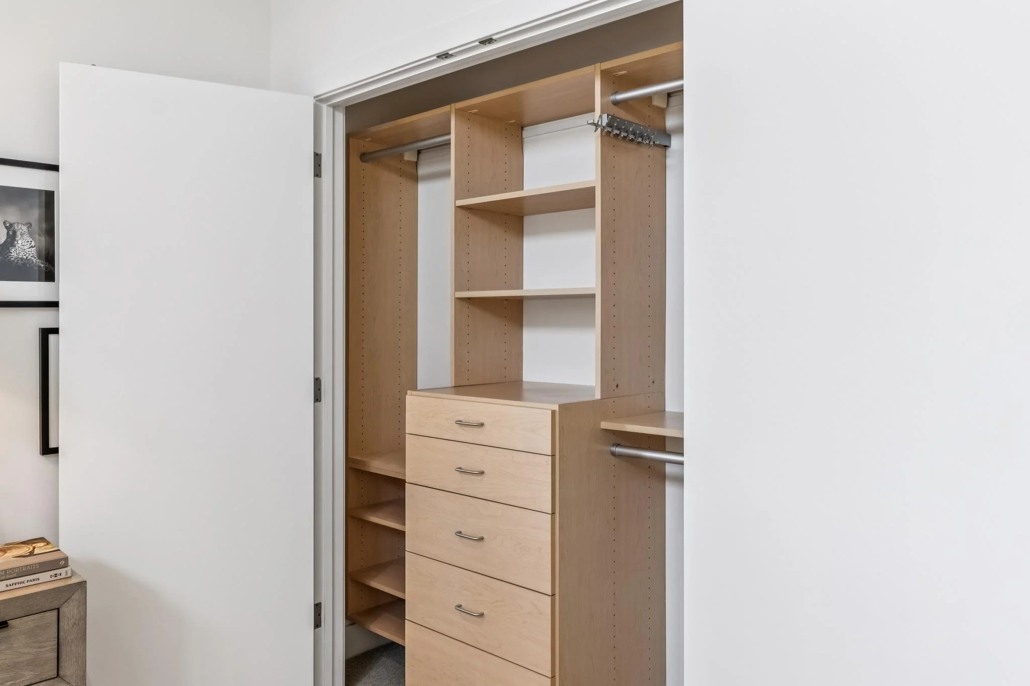 An empty closet with wooden shelves and drawers, with the door partially open in a minimalist room.