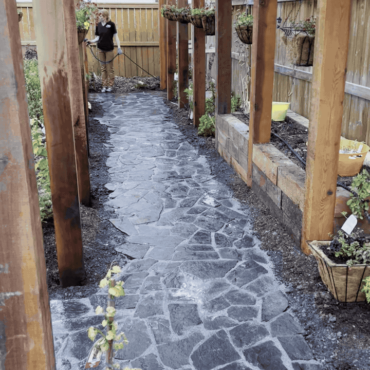 Person in a garden pathway working on a stone walkway.