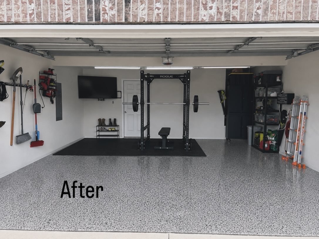 Clean, organized garage with workout equipment including a power rack with barbell, bench, wall-mounted TV, shelving unit with storage boxes, and tools hanging on the wall.