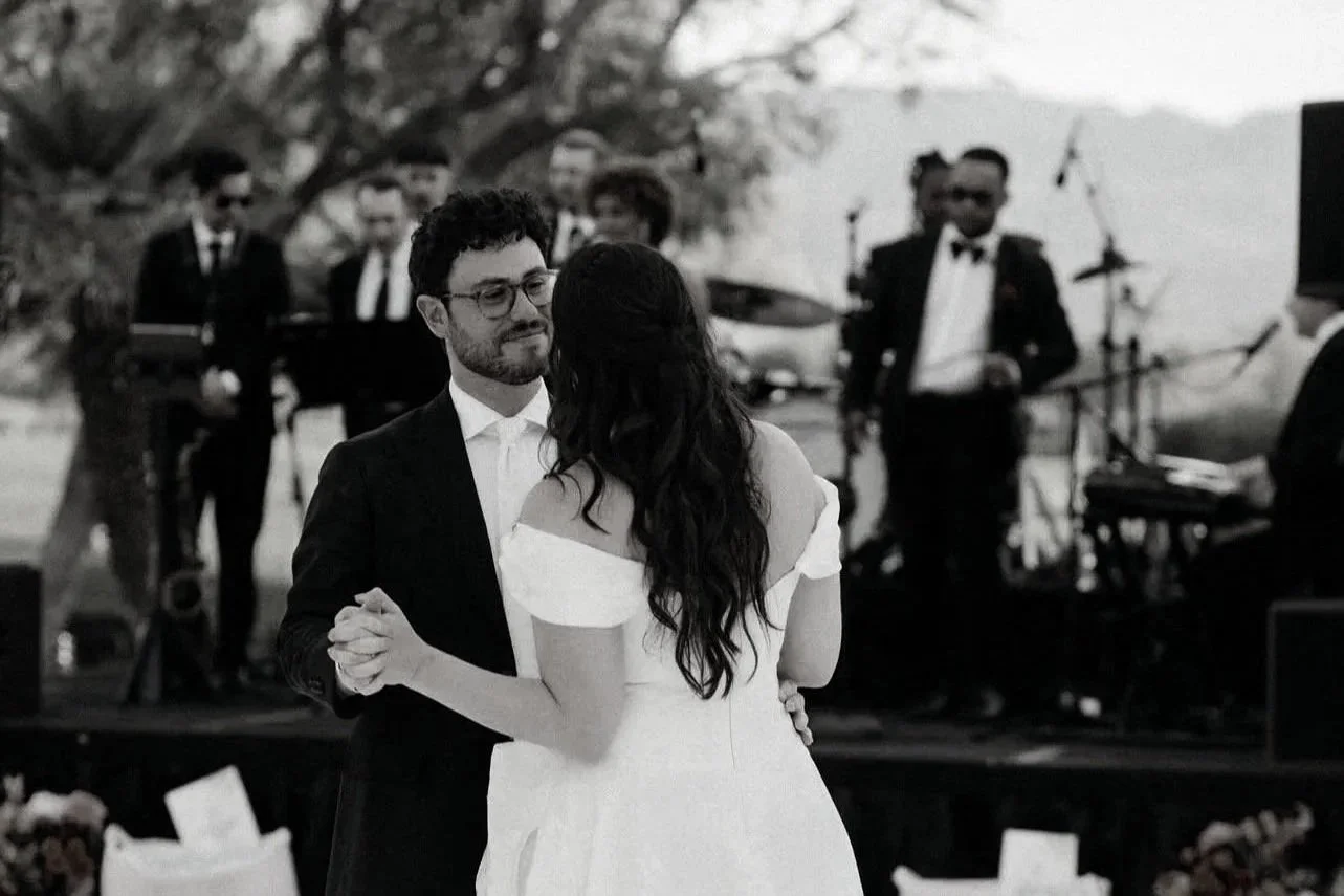 An image of a bride and groom sharing their first dance in a palm springs wedding with a full dance band behind them. 