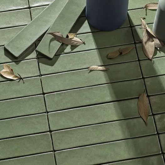 Green tiled floor with fallen brown leaves and a blue pot.