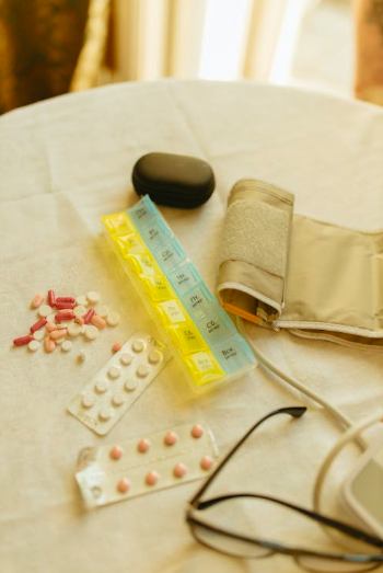 Various medication blister packs, pills, and a blood pressure cuff on a medical table.