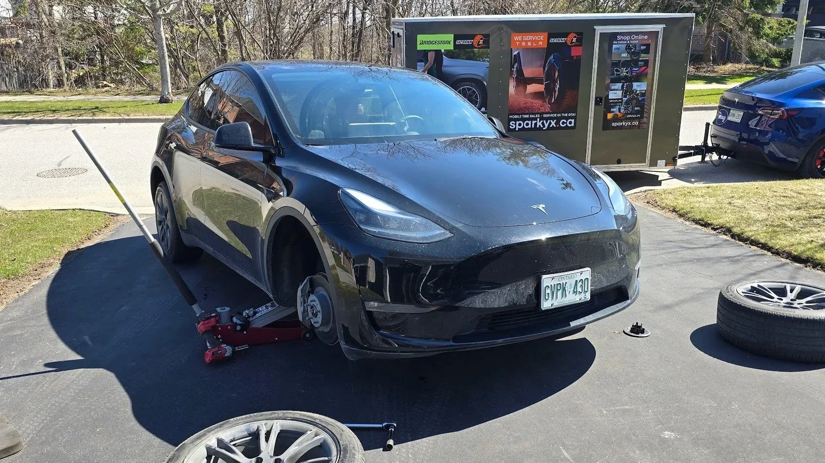 The High Voltage Tire service vehicle is parked near a driveway in Bowmanville, Ontario, where our technician is performing seasonal tire change for a Tesla Model Y.