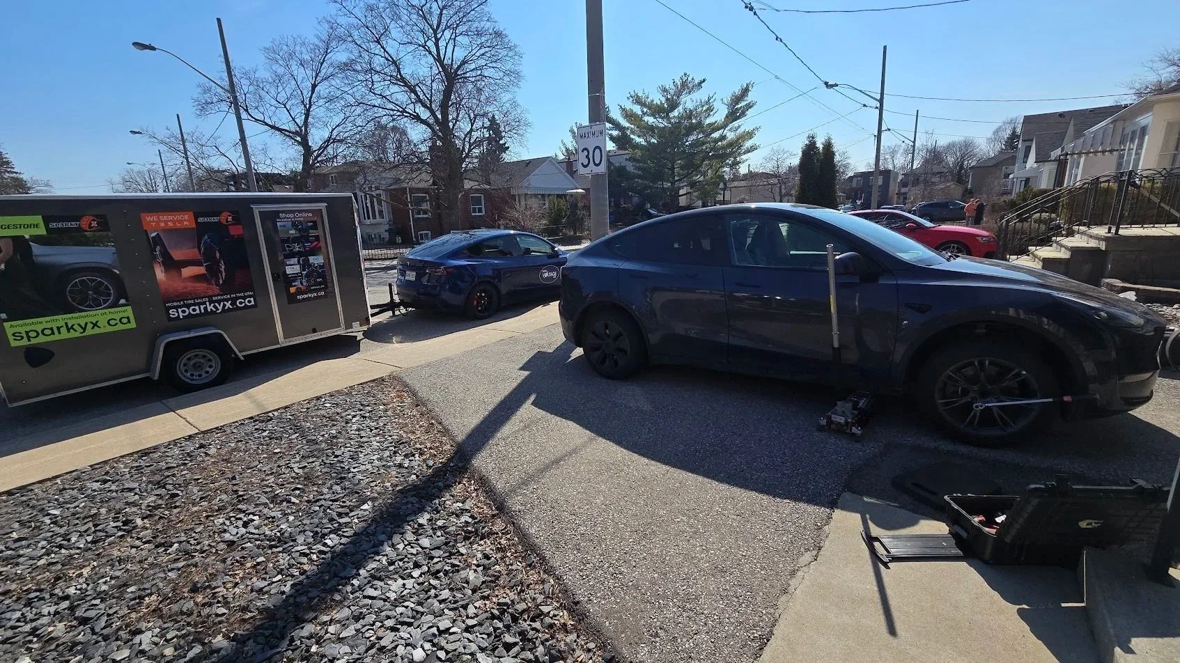 The High Voltage Tire service vehicle is parked near a driveway in Pickering, Ontario, where our technician is performing seasonal tire change for a Tesla Model Y