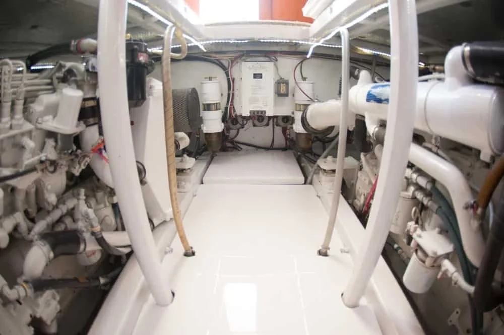 Engine room with white machinery, pipes, and electrical components.