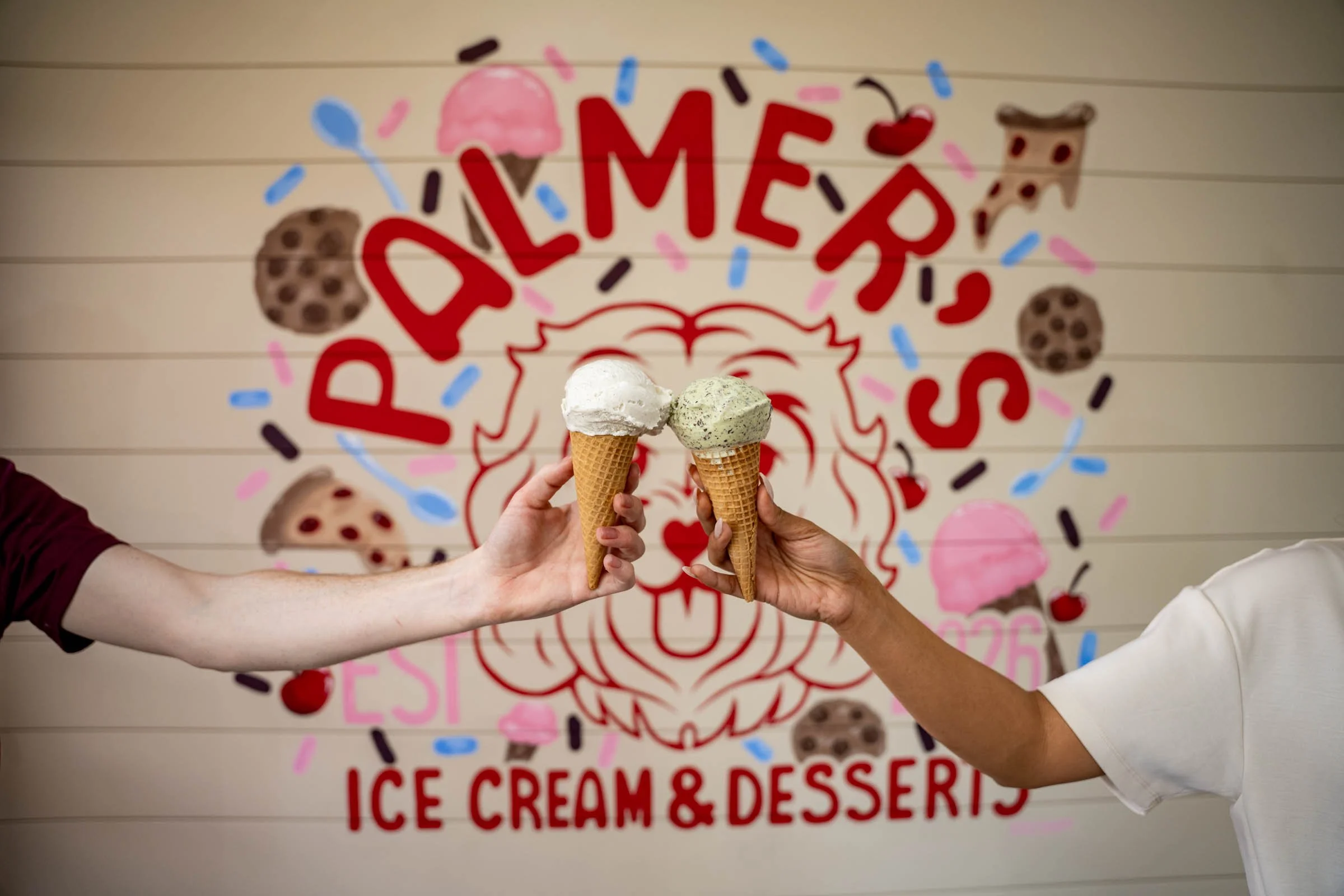 Two people holding ice cream cones in front of a festive sign that reads 'DREAM FEST' with ice cream & dessert illustrations.