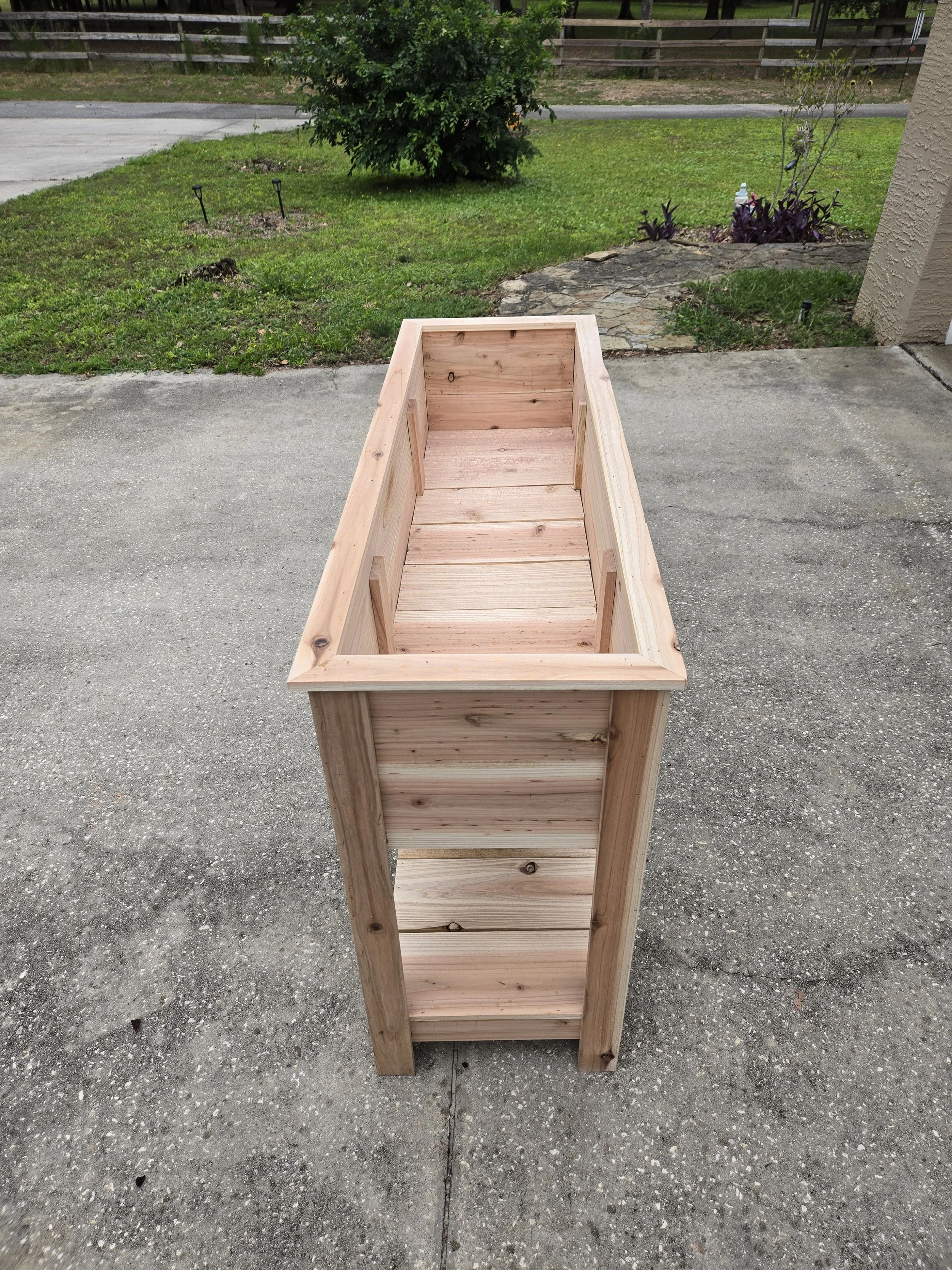 Cedar raised garden planter with bottom shelf standing in yard