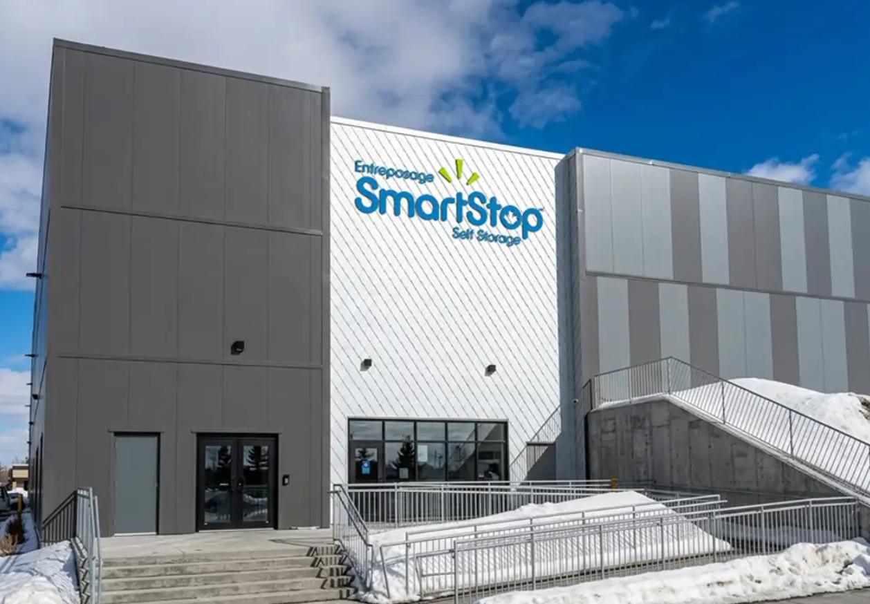 Exterior of a SmartStop self-storage facility with snow in the foreground and a blue sky above.