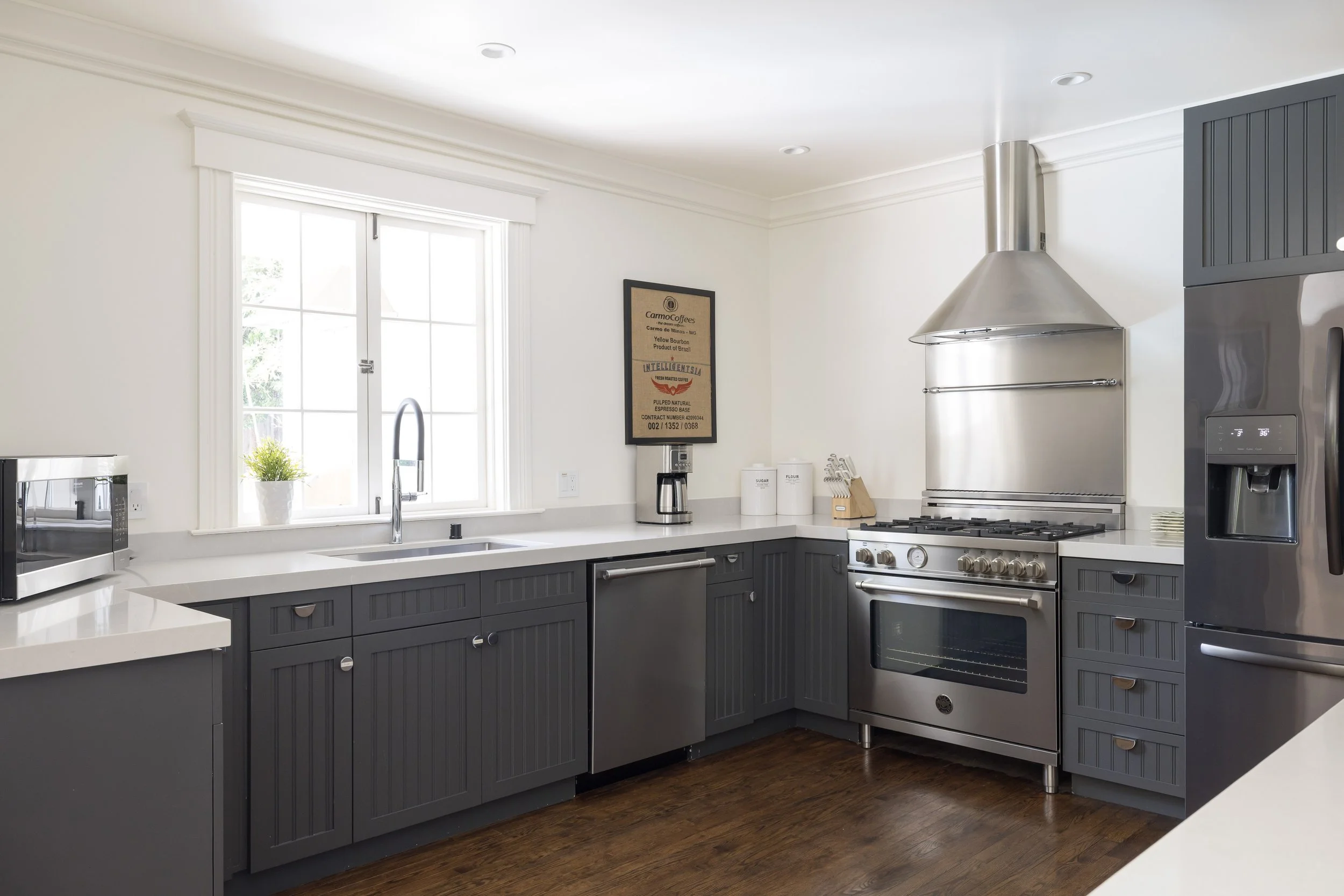 Modern kitchen with gray cabinets, stainless steel appliances, and a window over the sink.