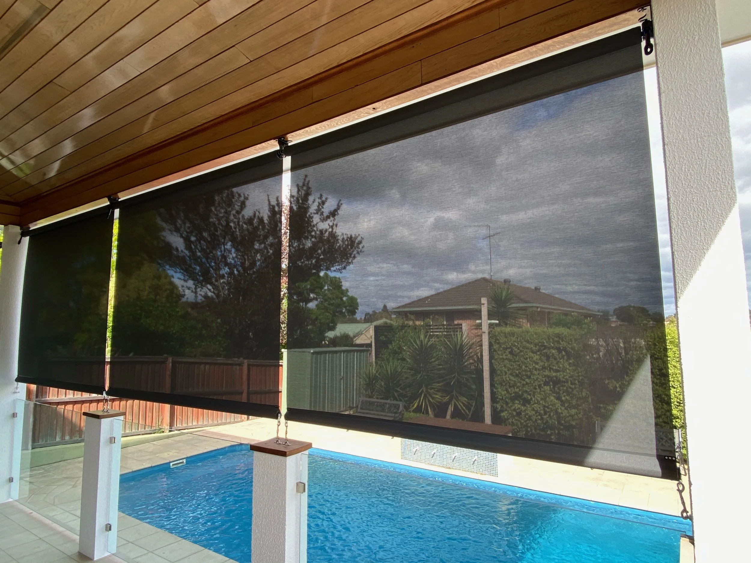 Straight drop blind above glass pool fence to control glare and light