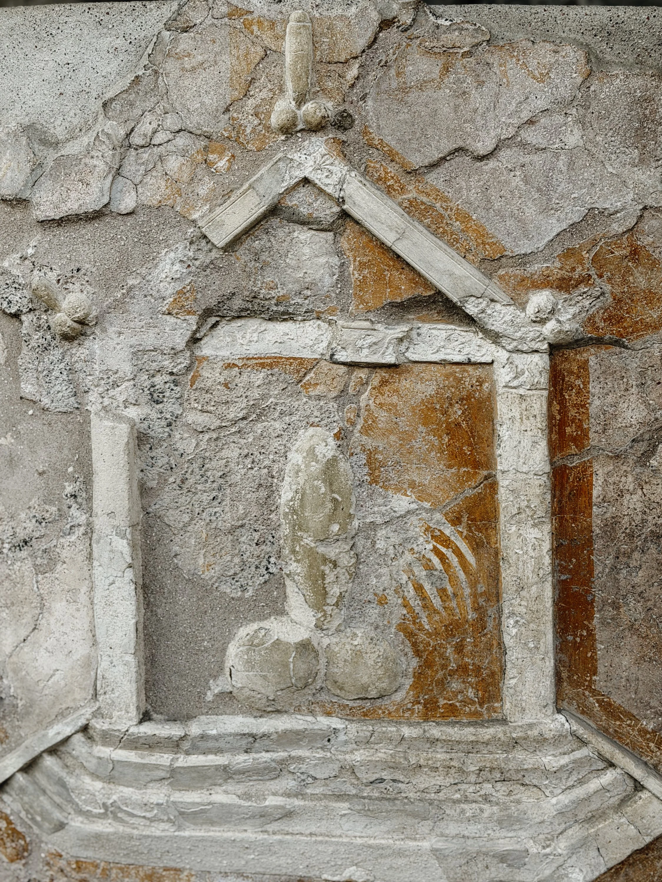 An ancient stone archway with remnants of decorative frescoes and worn bricks on a weathered wall.