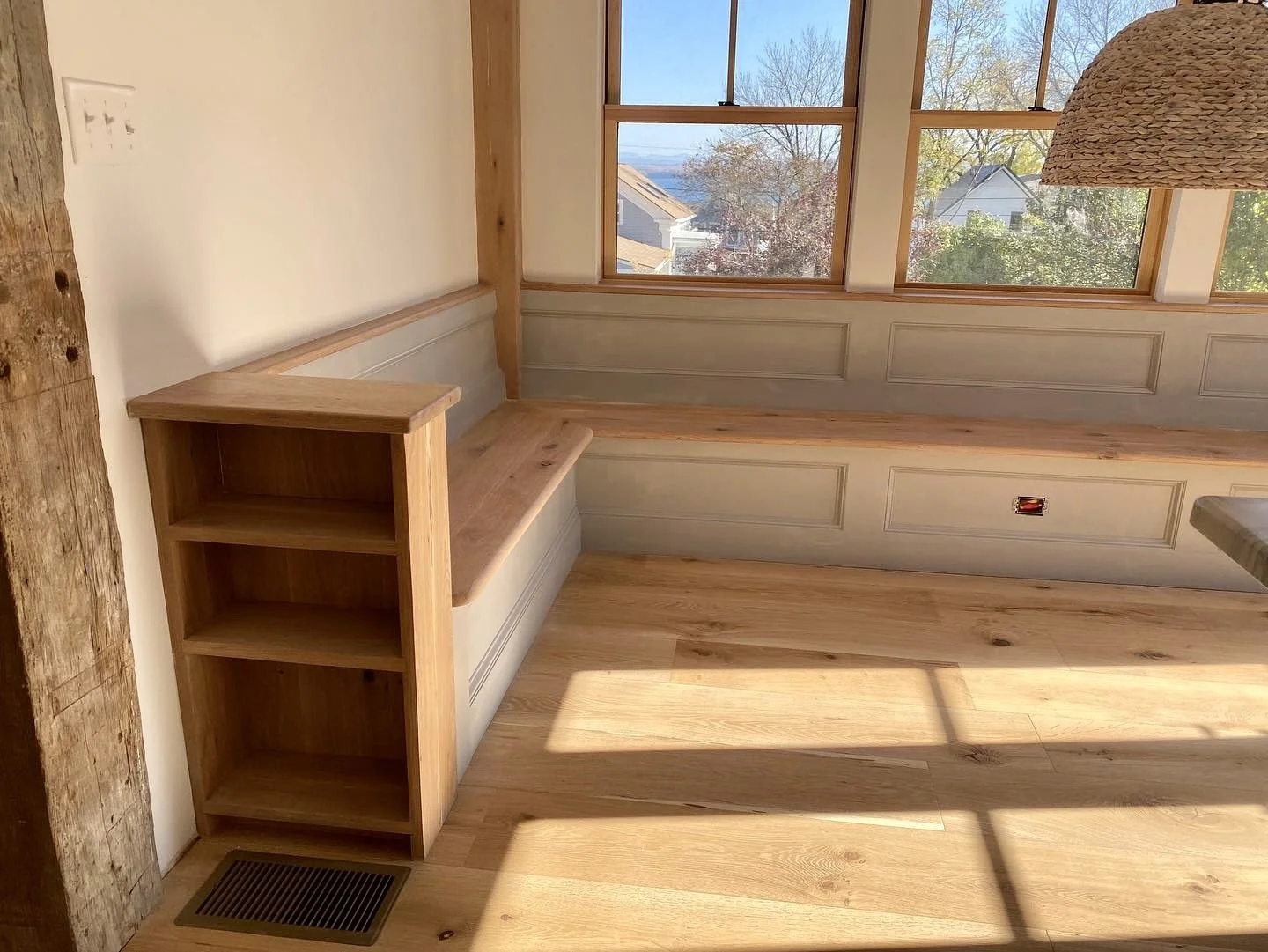 Custom built-in wooden bench and book shelf in breakfast nook.