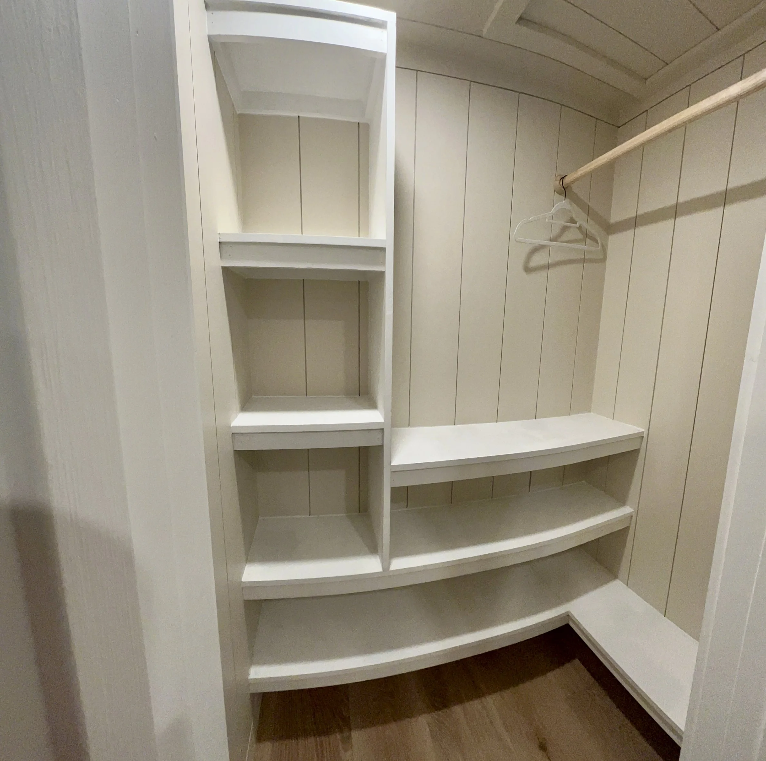 Empty white built-in bookshelf with three shelves located in a wood-paneled room.
