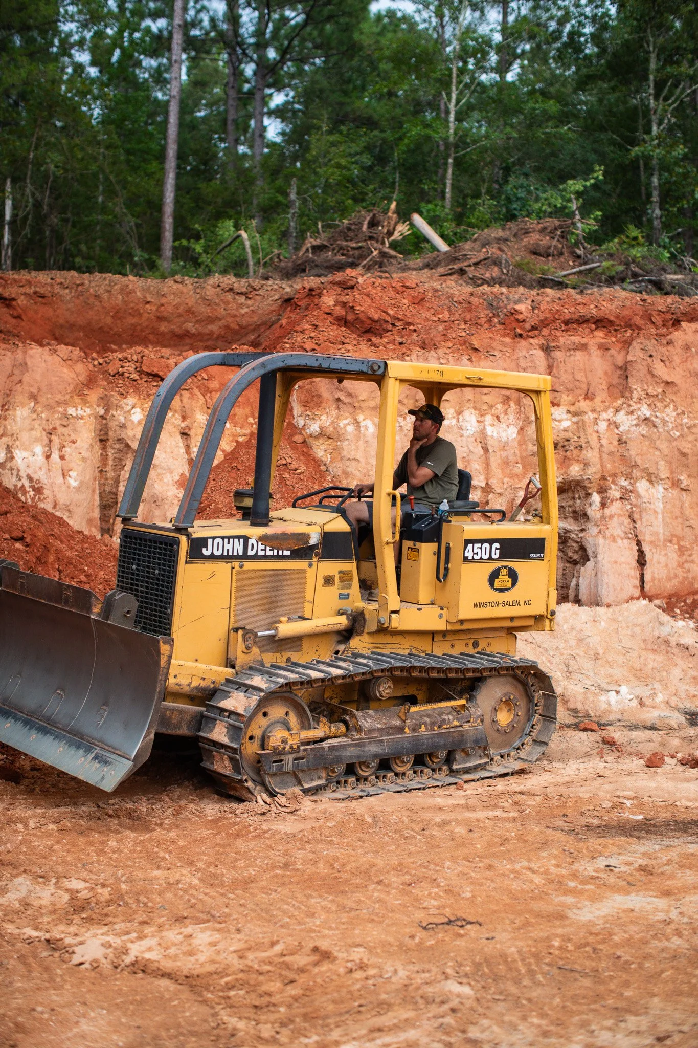 A man operating heavy equipment performing dirt work and site grading for properties near Aiken, SC.