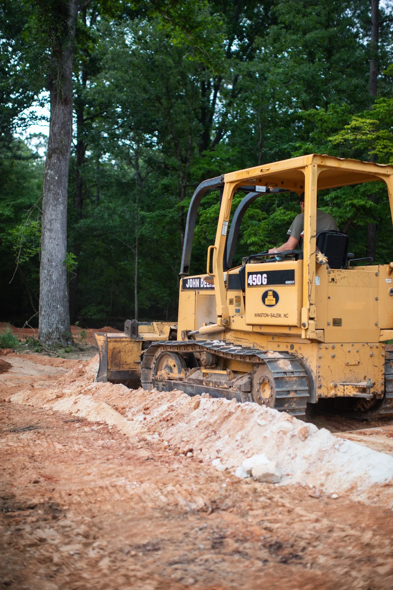 A yellow bulldozer moving dirt on a construction site surrounded by trees near Aiken, SC.