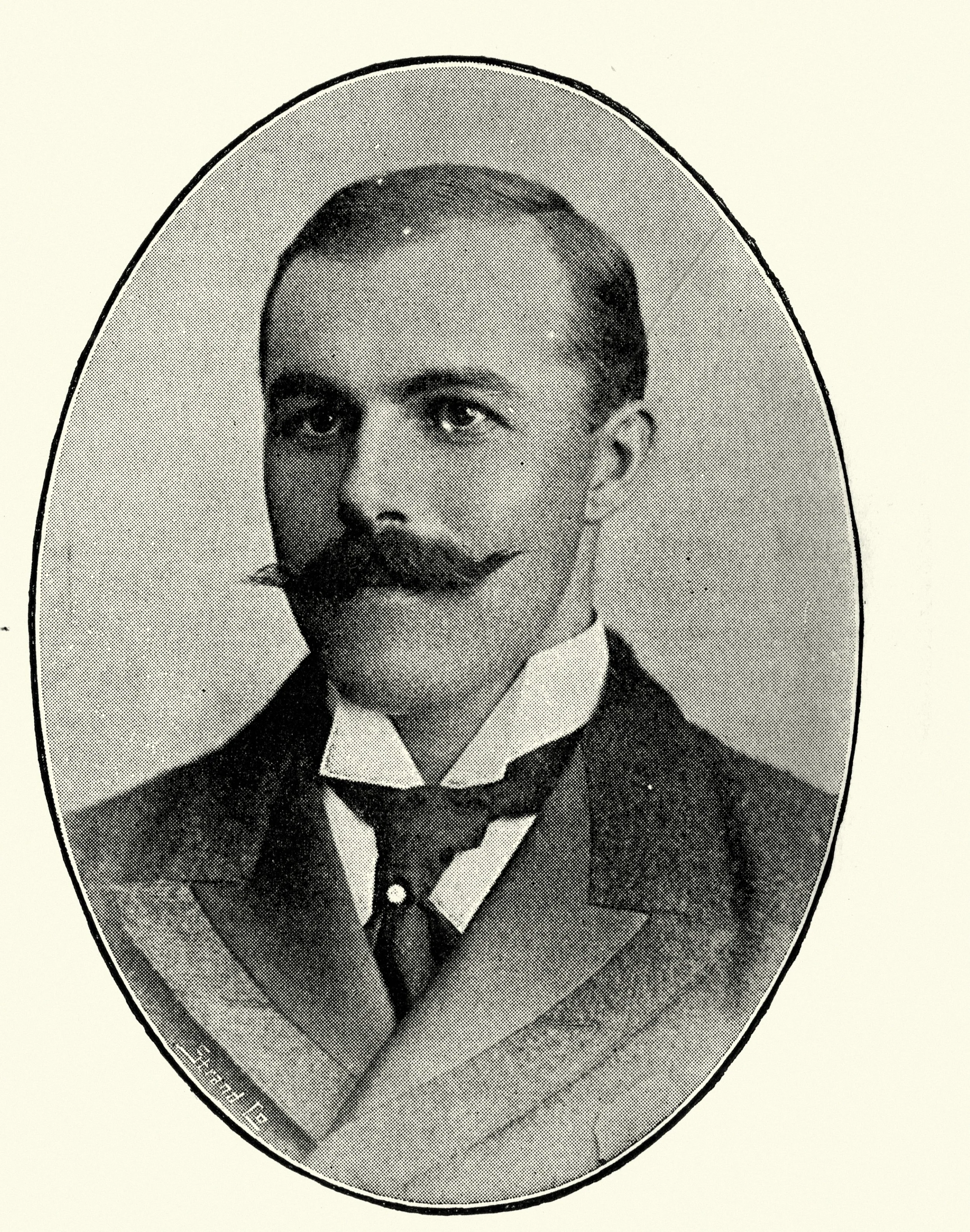 A black-and-white photograph of a portrait of a man with a mustache, dressed in a formal suit and tie, framed in an oval shape.