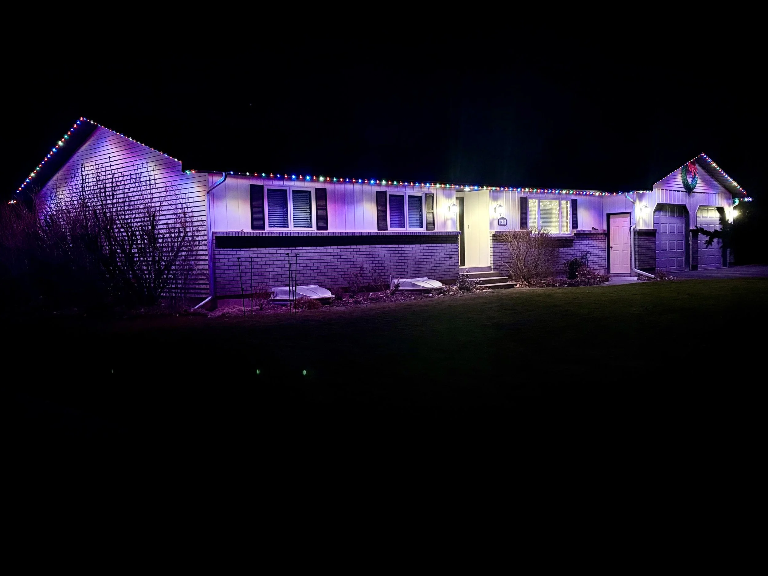 Nighttime view of a house decorated with colorful Christmas lights along the roofline and on the front porch
