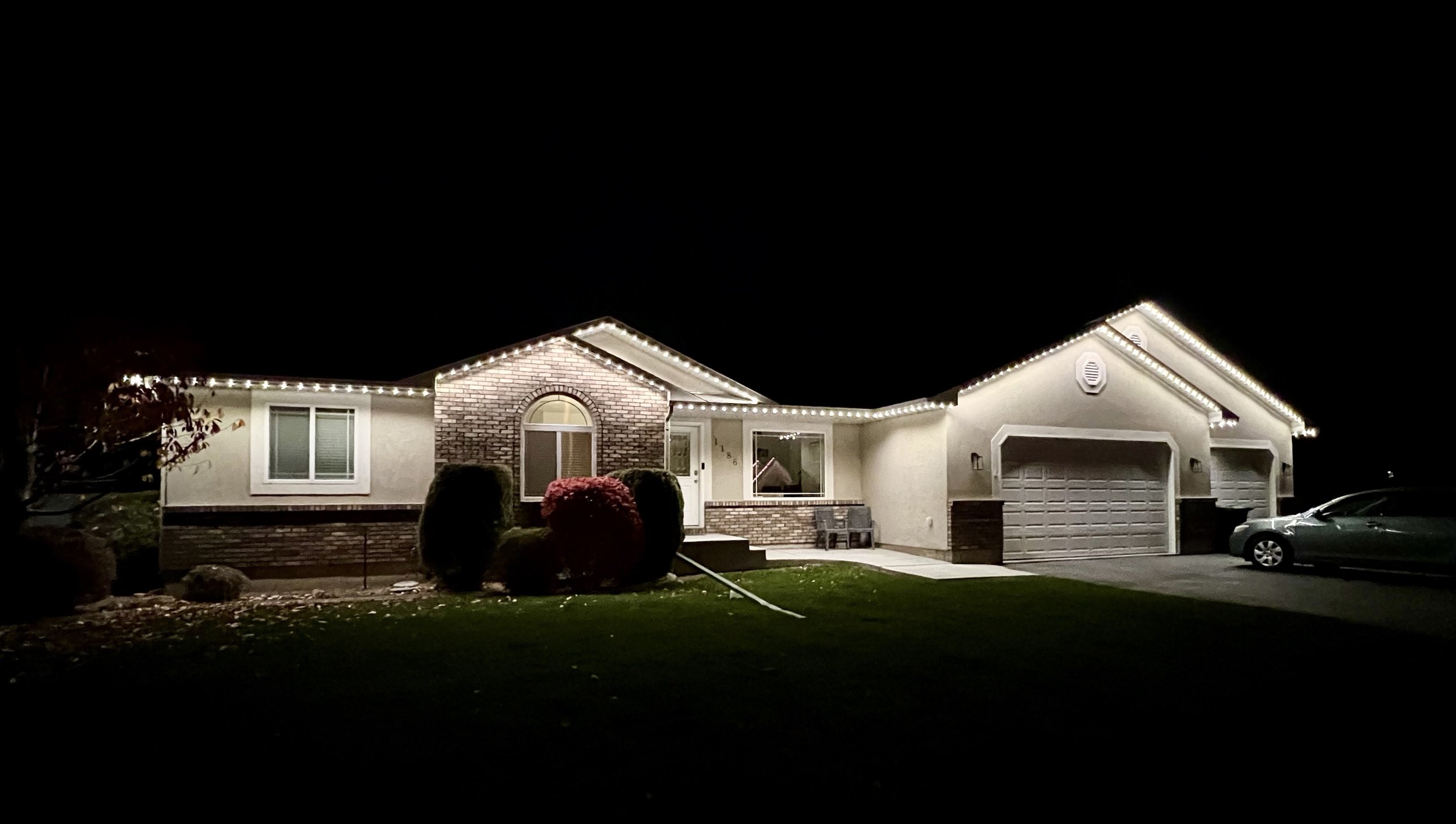 A house decorated with string lights along the roofline at night.