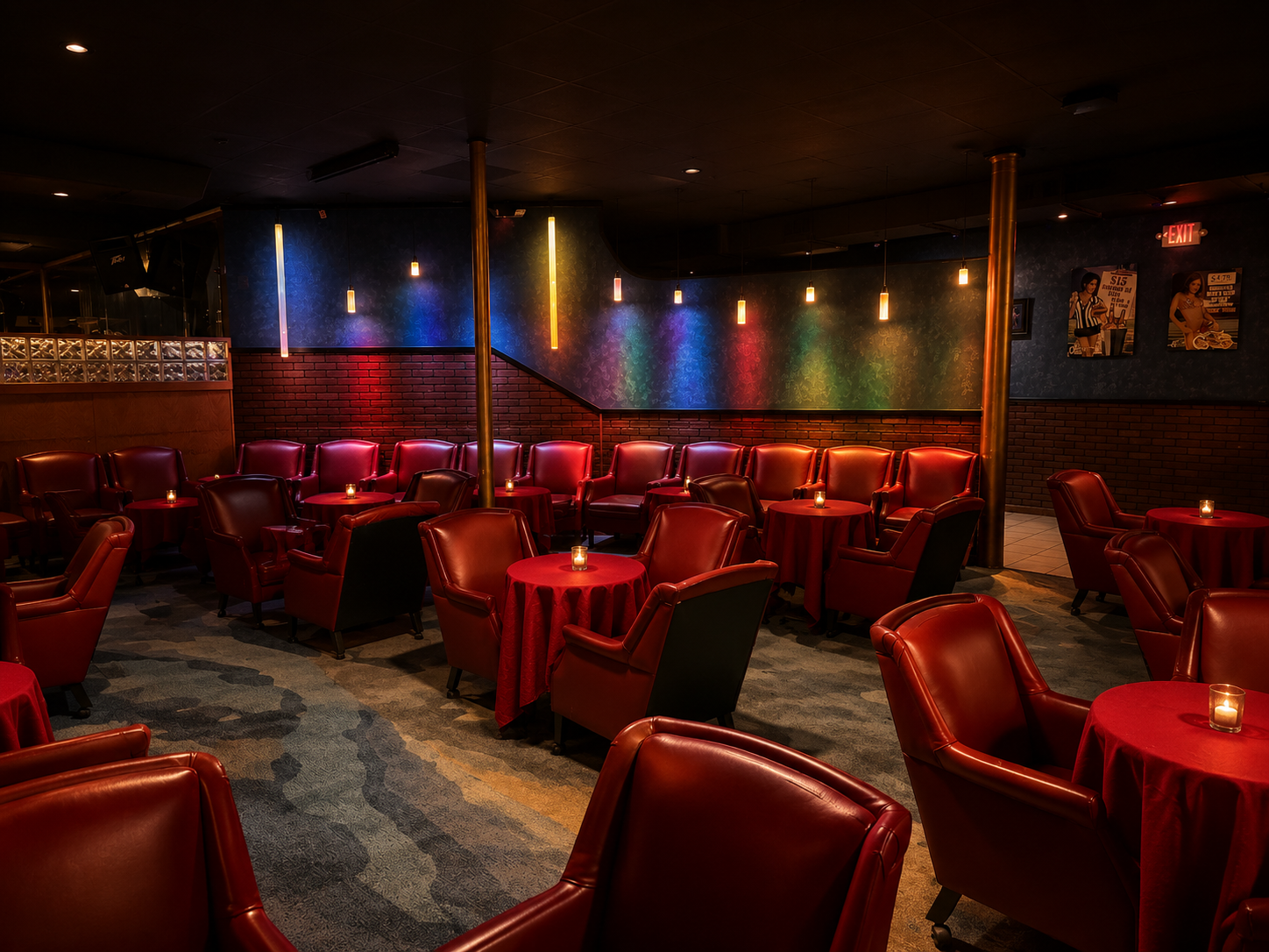 An empty lounge or bar with red leather chairs and round tables with red tablecloths, small candles, and colorful lighting on the wall, creating a cozy atmosphere.