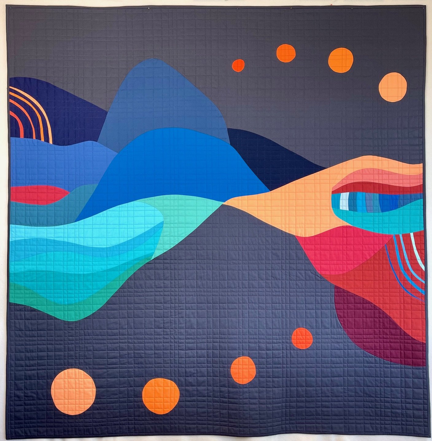 An abstract quilt with colorful flowing shapes and geometric patterns on a dark background.