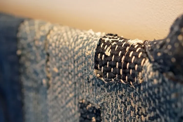 Close-up of a denim fabric with a black and white textured patch on the seam.